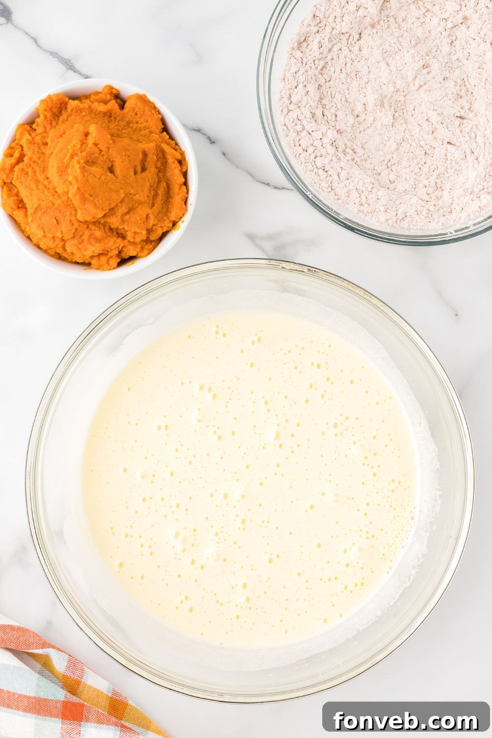 Classic Spiced Pumpkin Roll 8 wet ingredients mixed up in a glass bowl on table for making Pumpkin Cake Roll