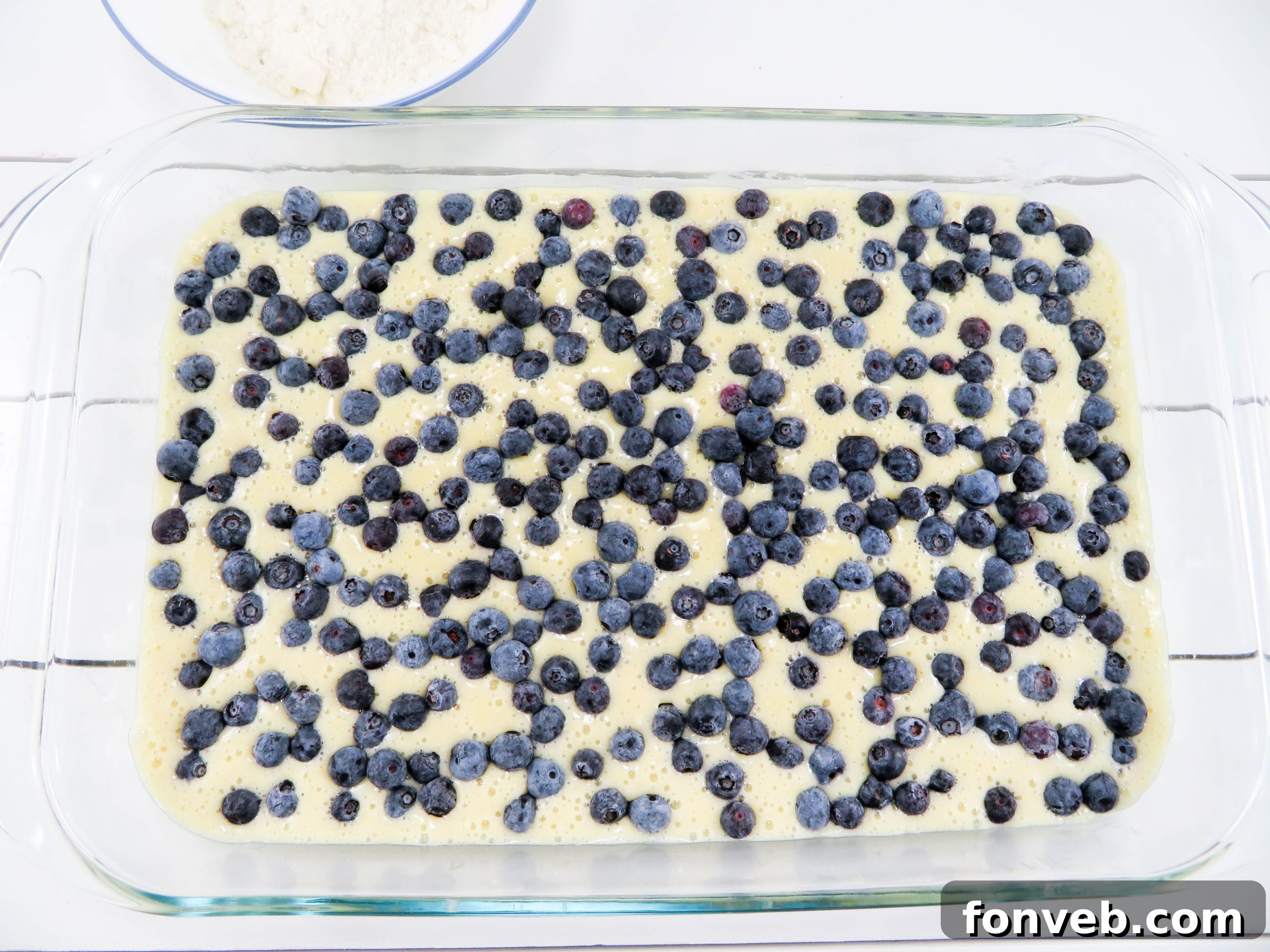 A whole blueberry butter cake, golden brown and covered with a light crumb topping, ready to be sliced
