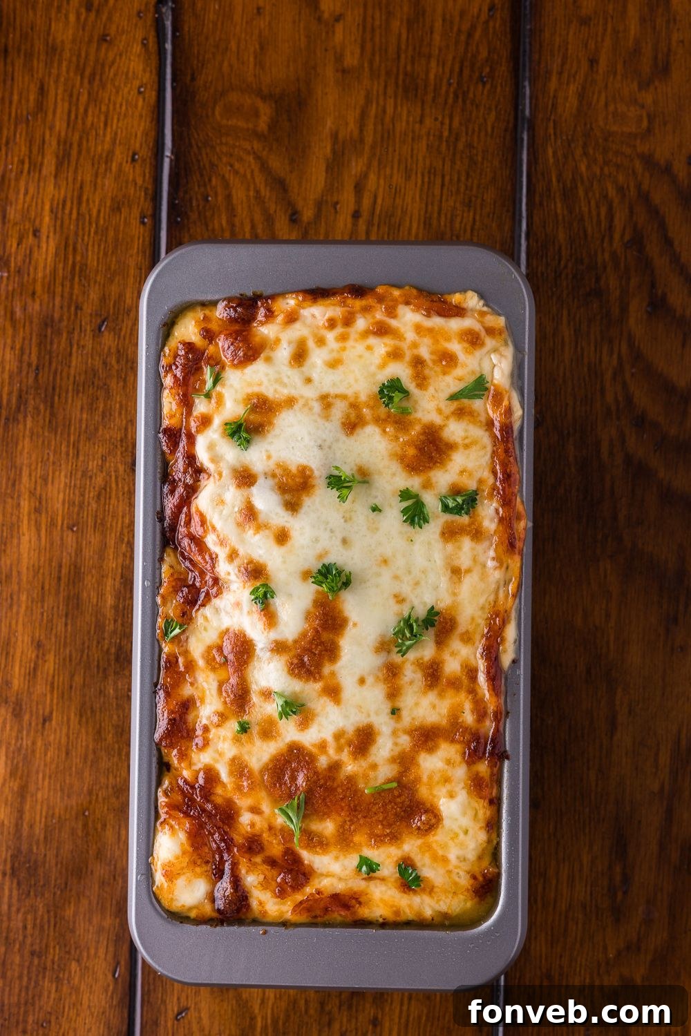 Stuffed Philly Cheesesteak Meatloaf baked and sitting in a loaf pan on wooden table 