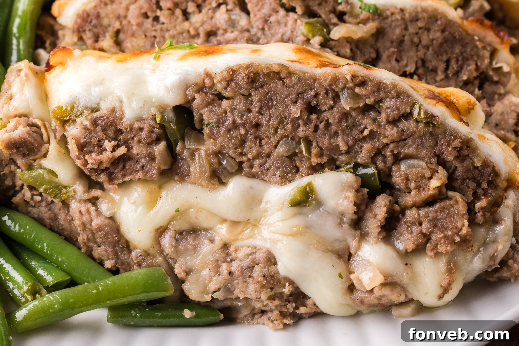 Up close shot of the cheesy inside of the Philly Cheesesteak Meatloaf sliced on a white serving plate 