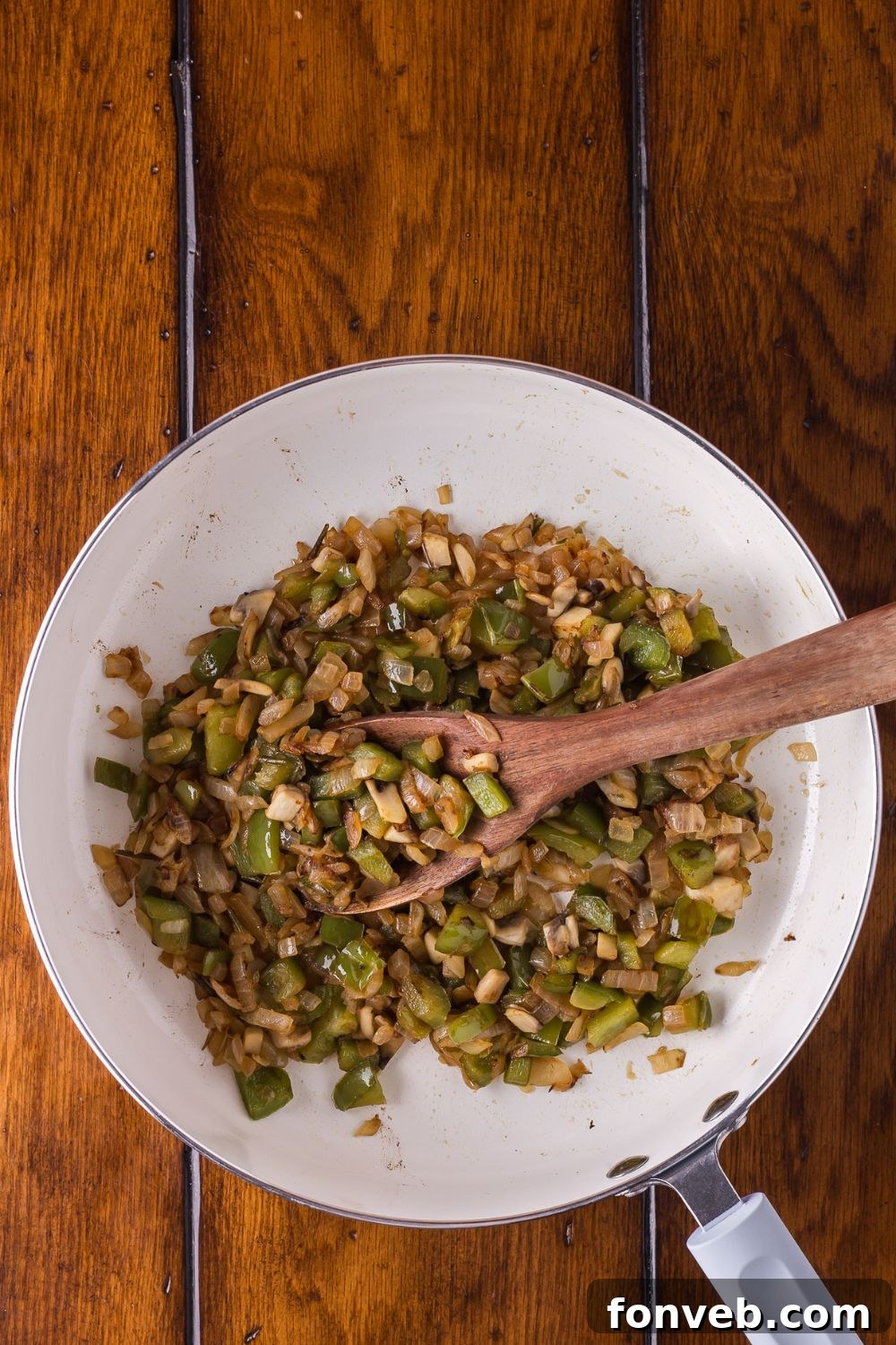 sauted onions and peppers cooked in a skillet on a wooden table 