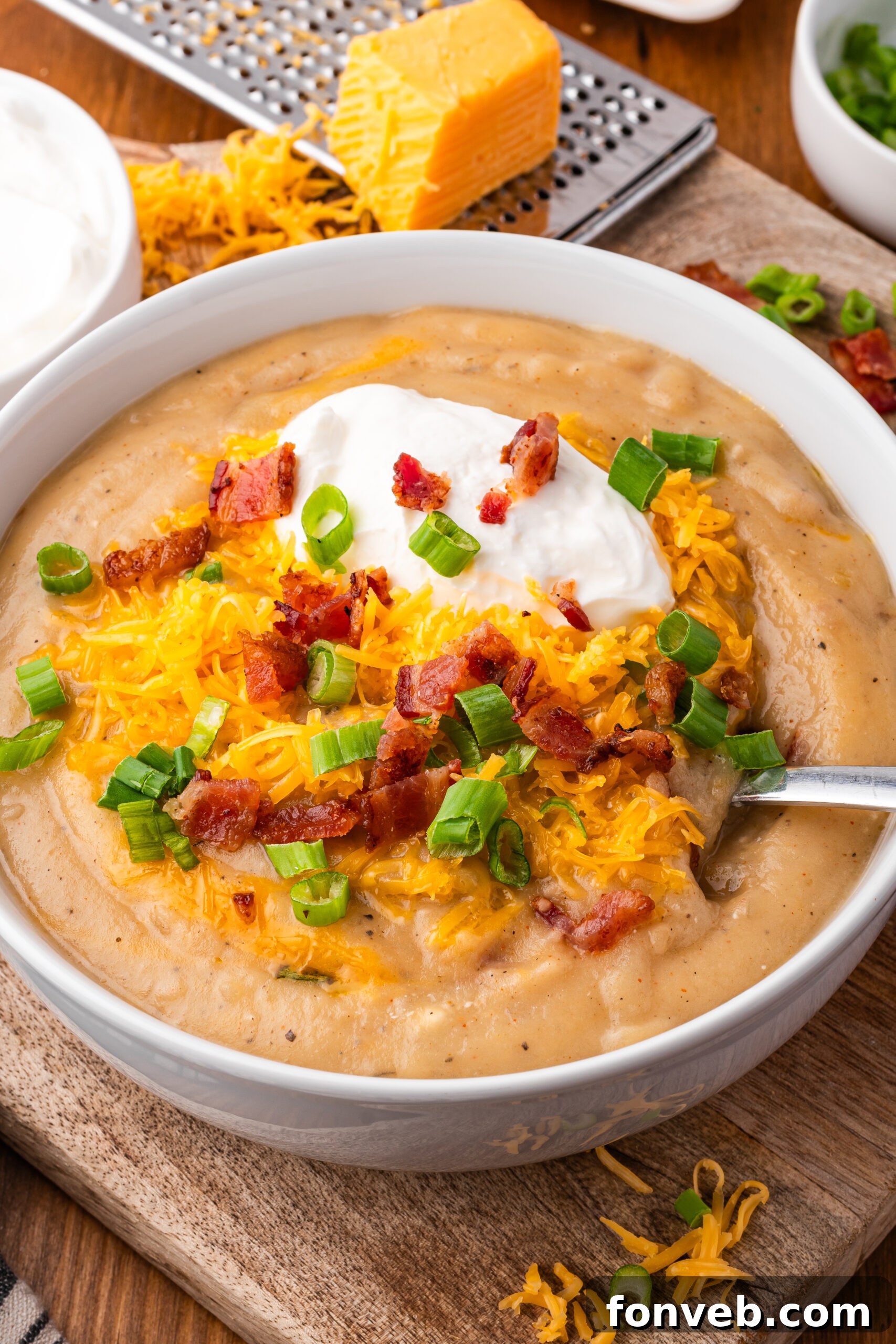 up close shot of the Crock pot loaded baked potato soup in a white bowl topped with bacon, cheese and sour cream