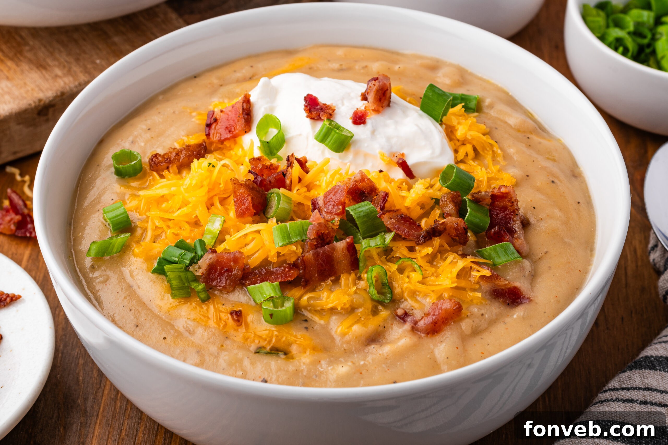 up close shot of the Crock pot loaded baked potato soup in a white bowl topped with bacon, cheese and sour cream