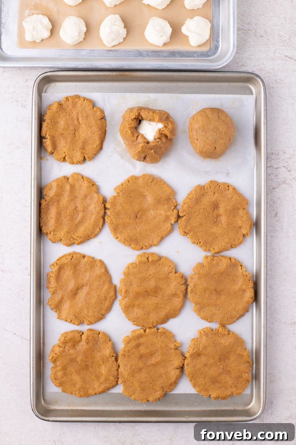 cheesecake filling in center of one cookie on a baking sheet on table