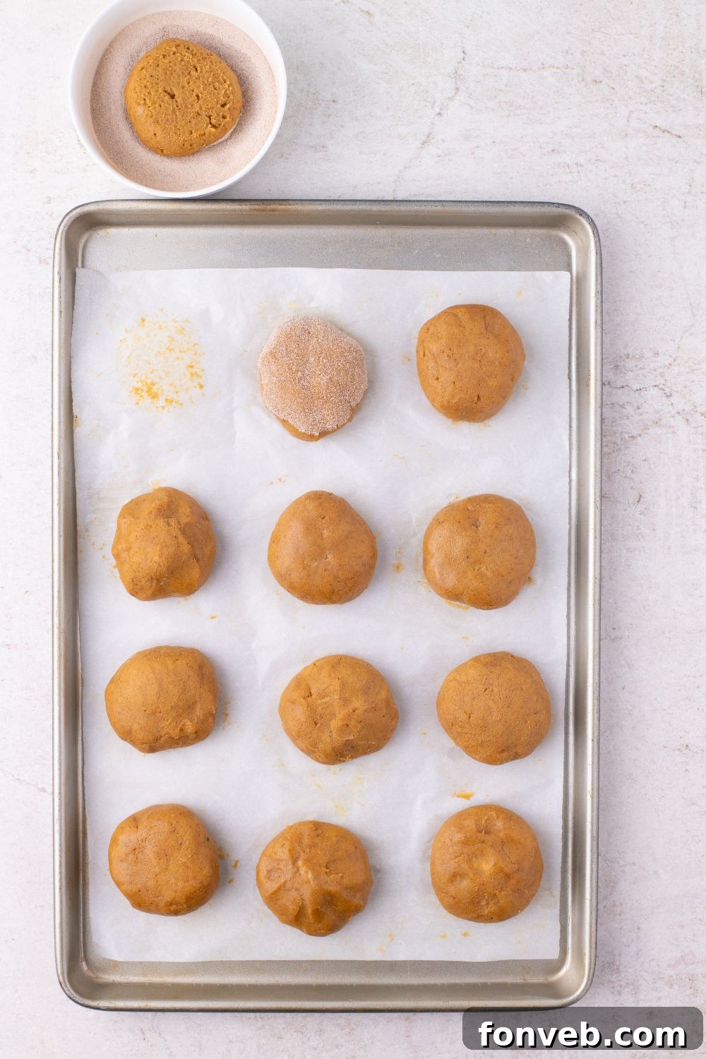raw pumpkin cookie dough on baking sheet with cinnamon sugar coating on cookie balls 
