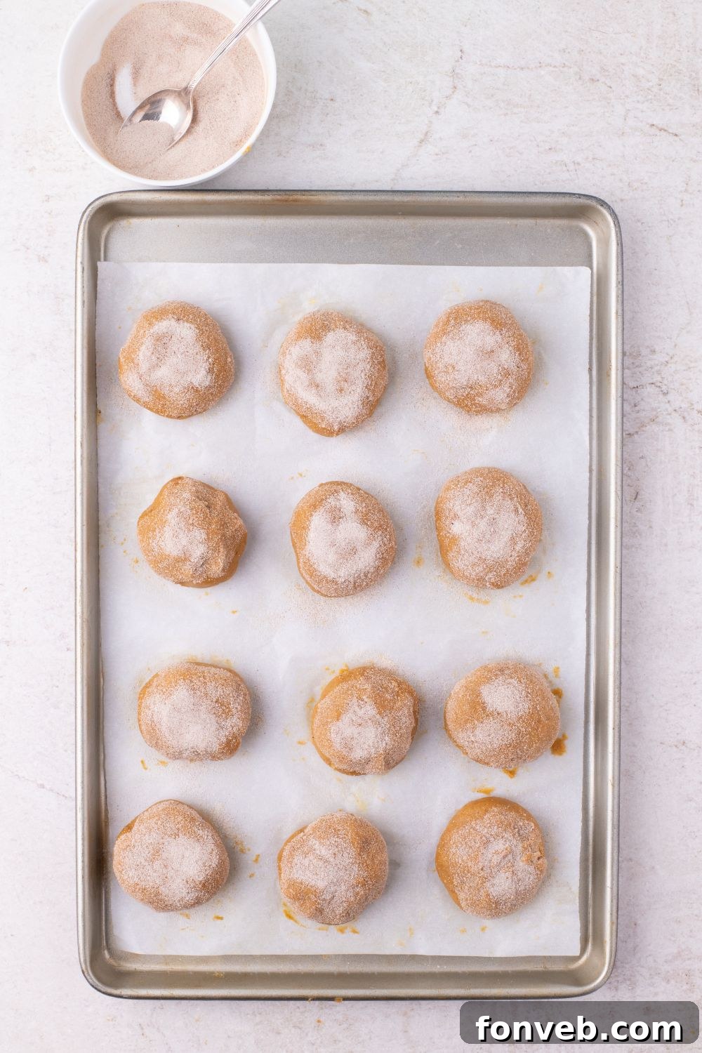 cinnamon sugar coated pumpkin cheesecake stuffed cookies on a baking tray 