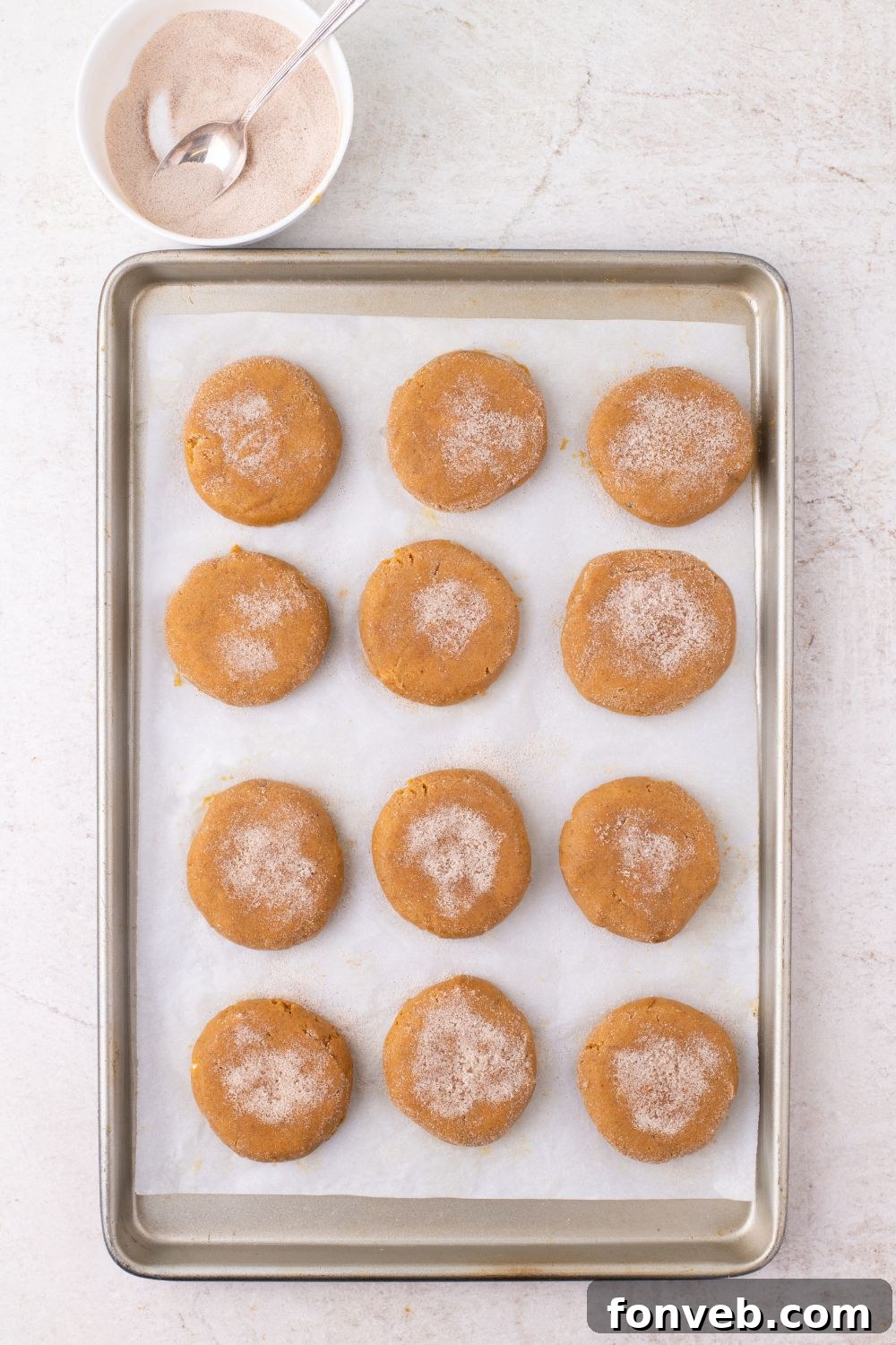 cinnamon sugar coated pumpkin cheesecake stuffed cookies on a baking tray 