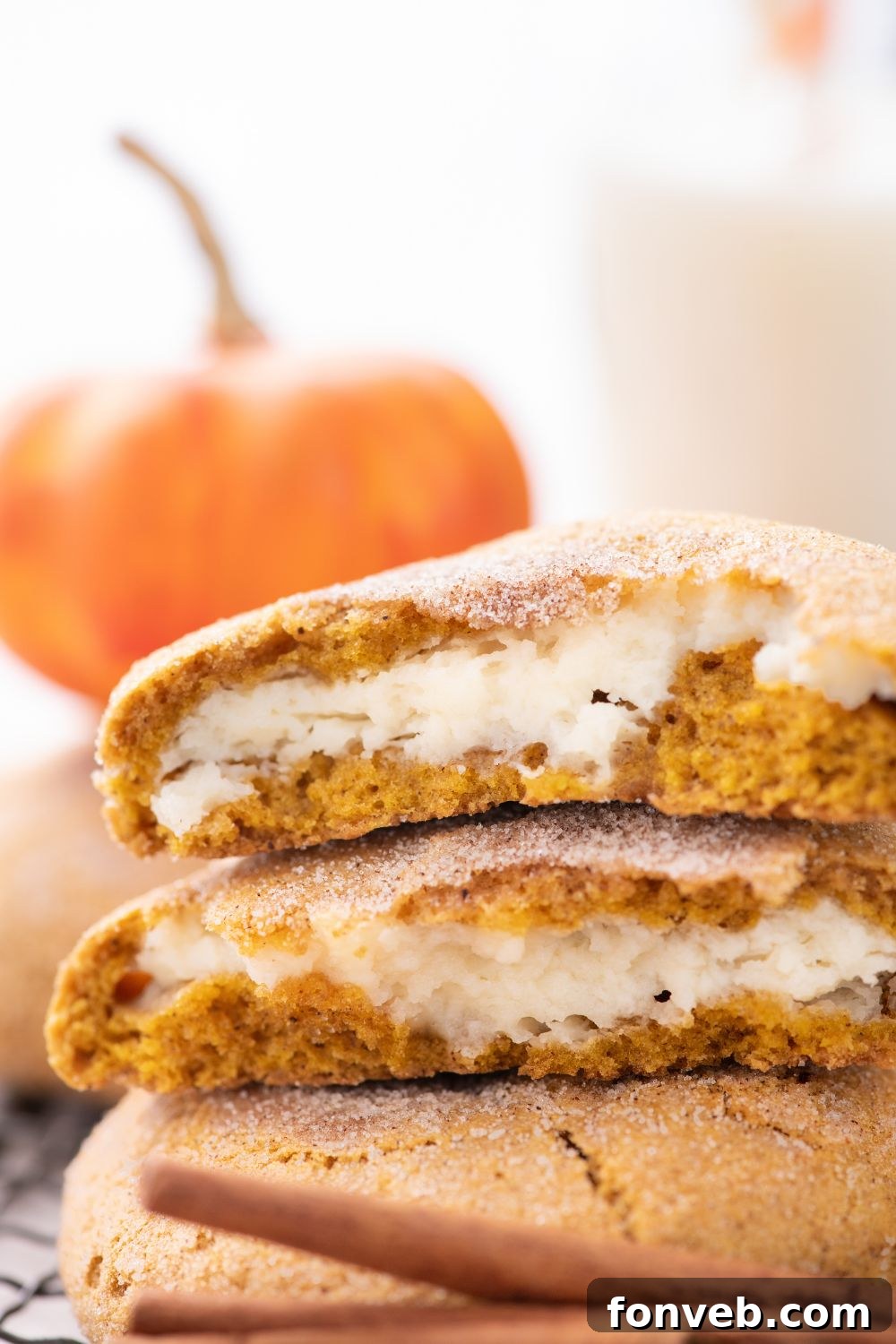 Pumpkin Cheesecake Cookies on table with one cookie torn in half sitting on top of stack