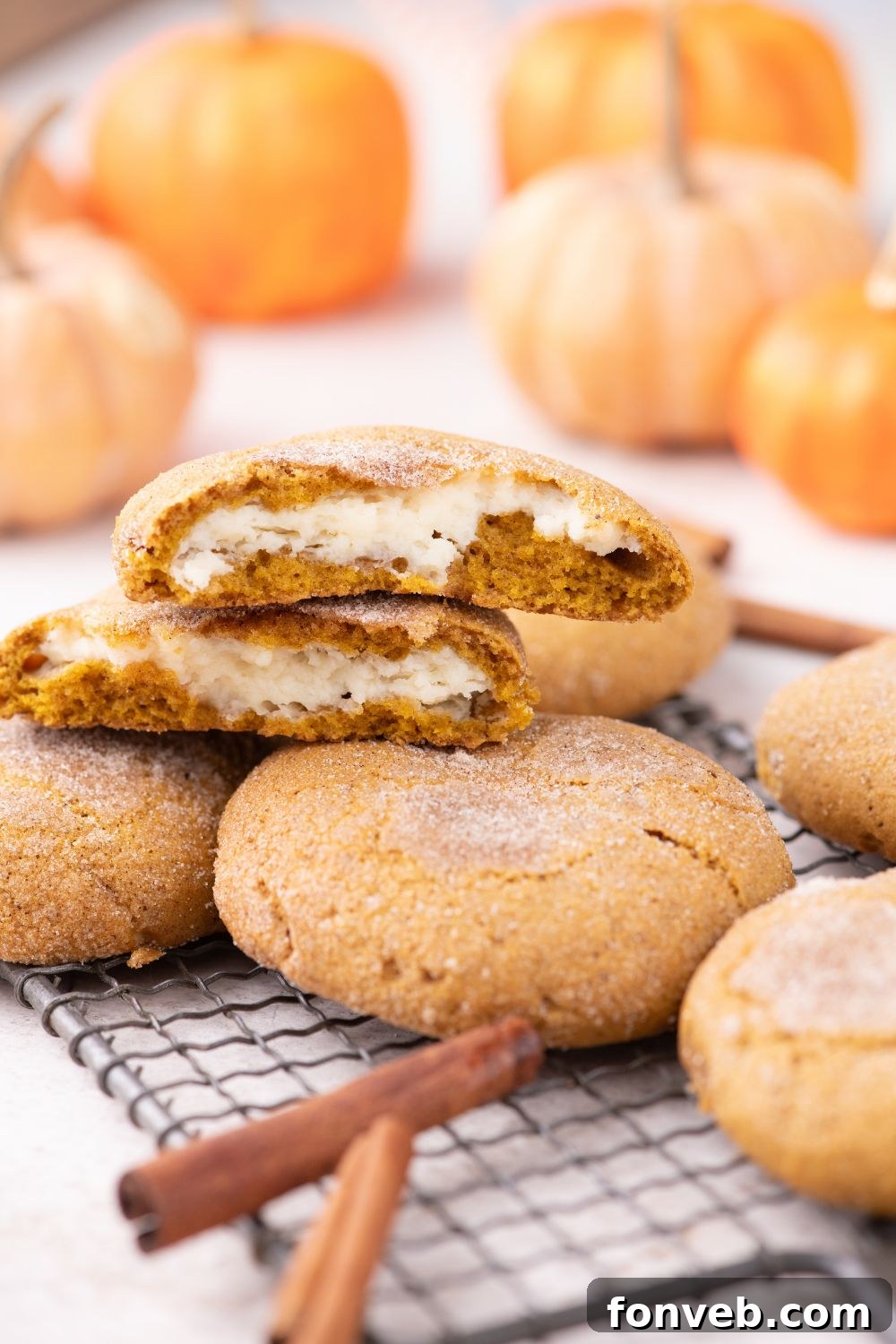 cooling rack on table with a pumpkin cheesecake cookie in center with pumpkins in background 