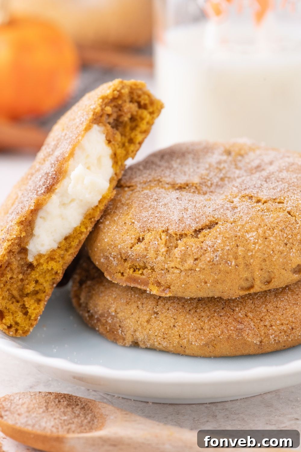 white plate sitting on table with two cookies on plate with one cookie cut in half and placed sideways on plate