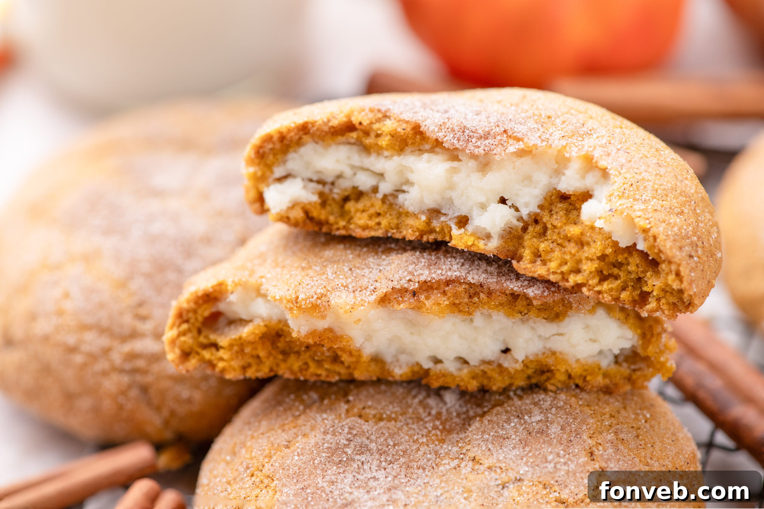 Pumpkin Cheesecake Cookies stacked on a cooling rack with one cut open