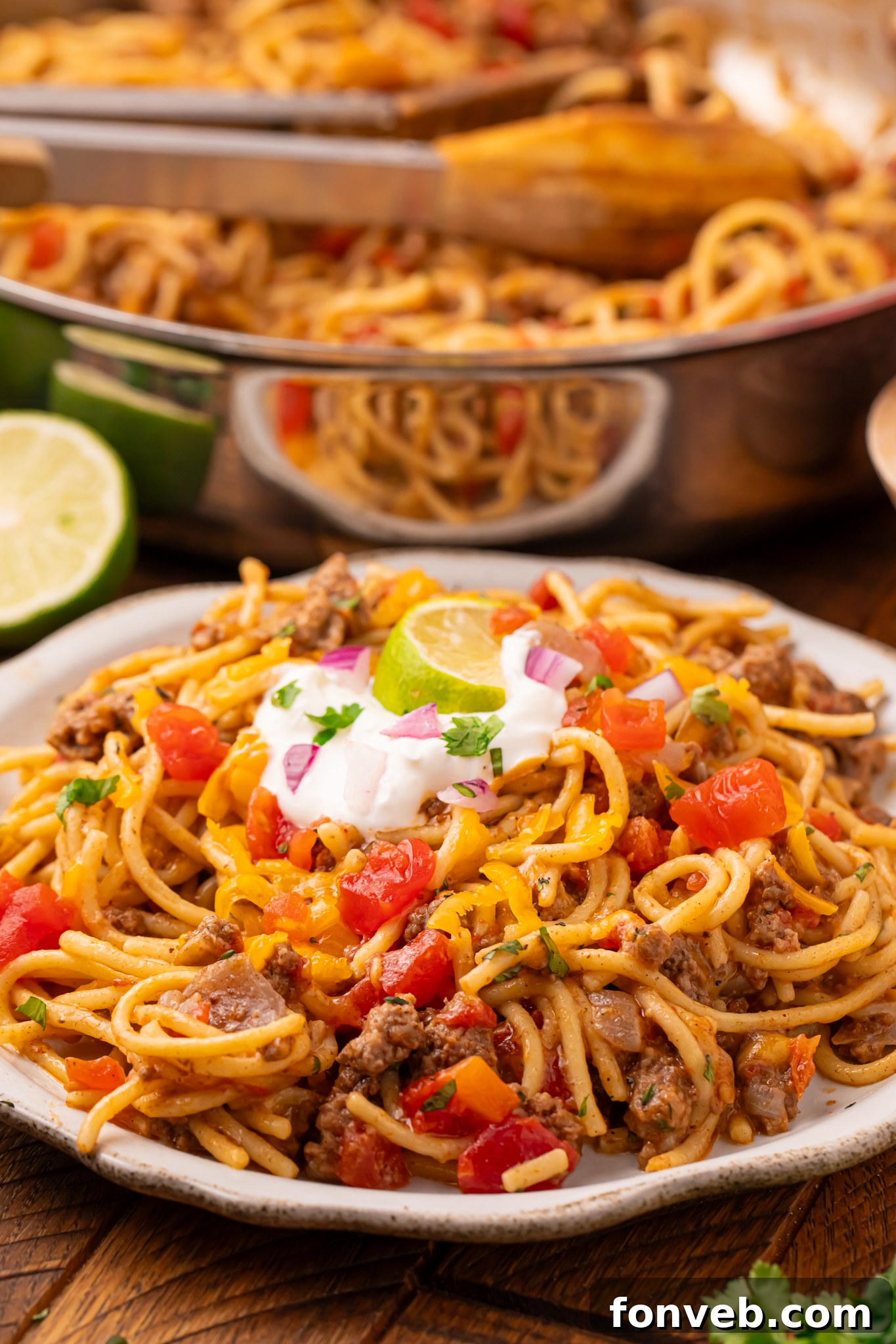One Pot Cheesy Taco Spaghetti 2 Cheesy Taco Spaghetti on a white plate sitting on a dark wood table