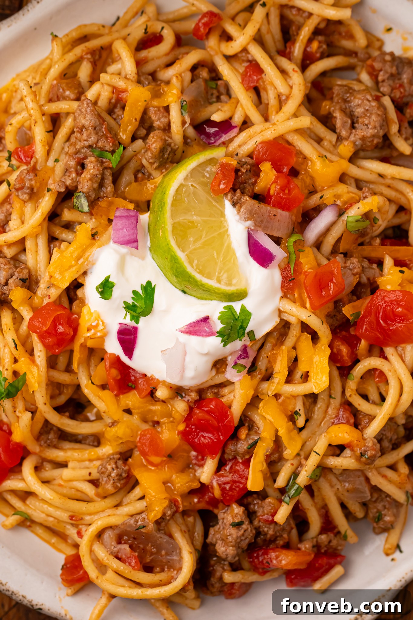 One Pot Cheesy Taco Spaghetti 18 Plate of Cheesy Taco Spaghetti topped with sour cream and lime