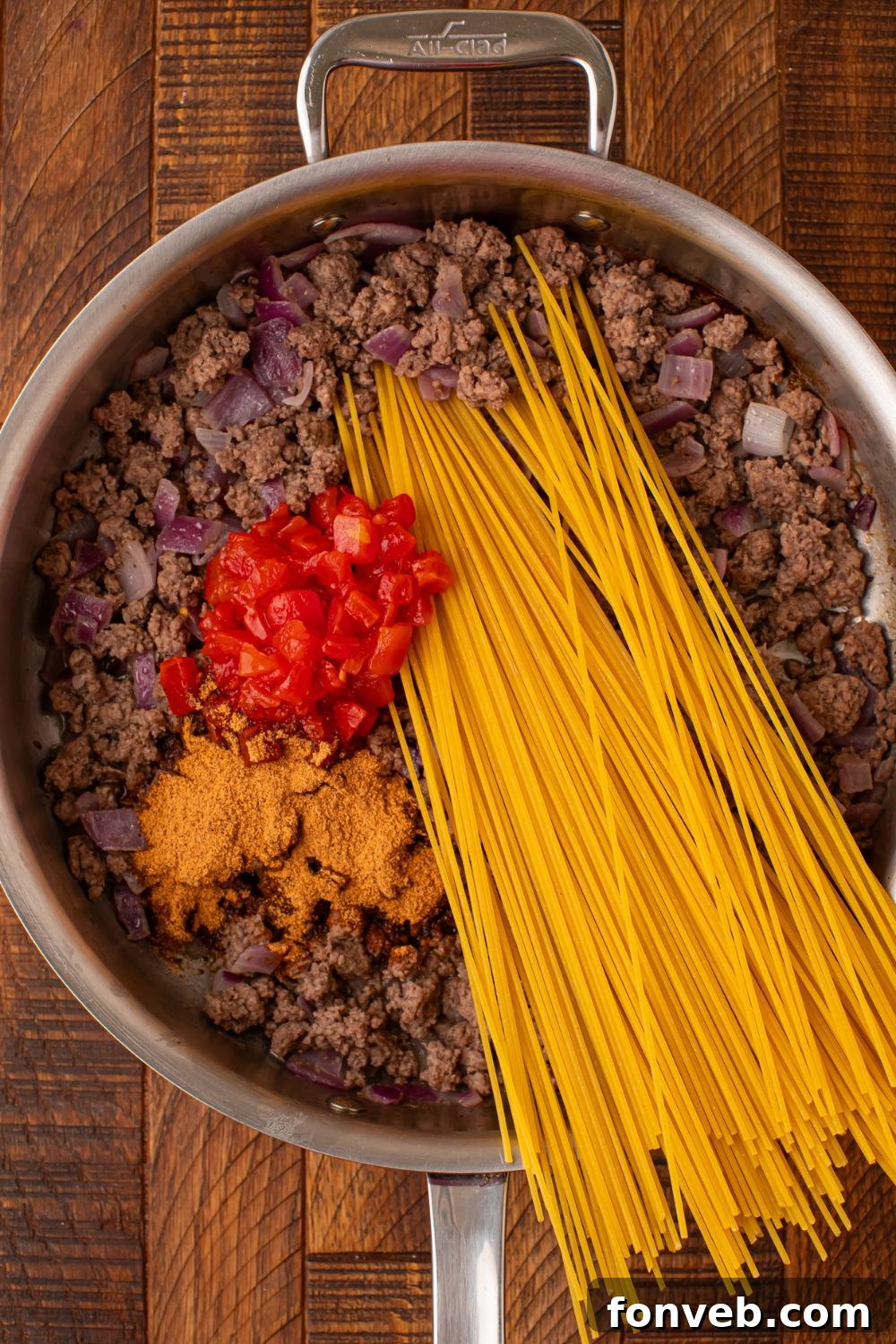 One Pot Cheesy Taco Spaghetti 7 ground beef, tomatoes, taco seasoning and dry pasta in a skillet on wooden table