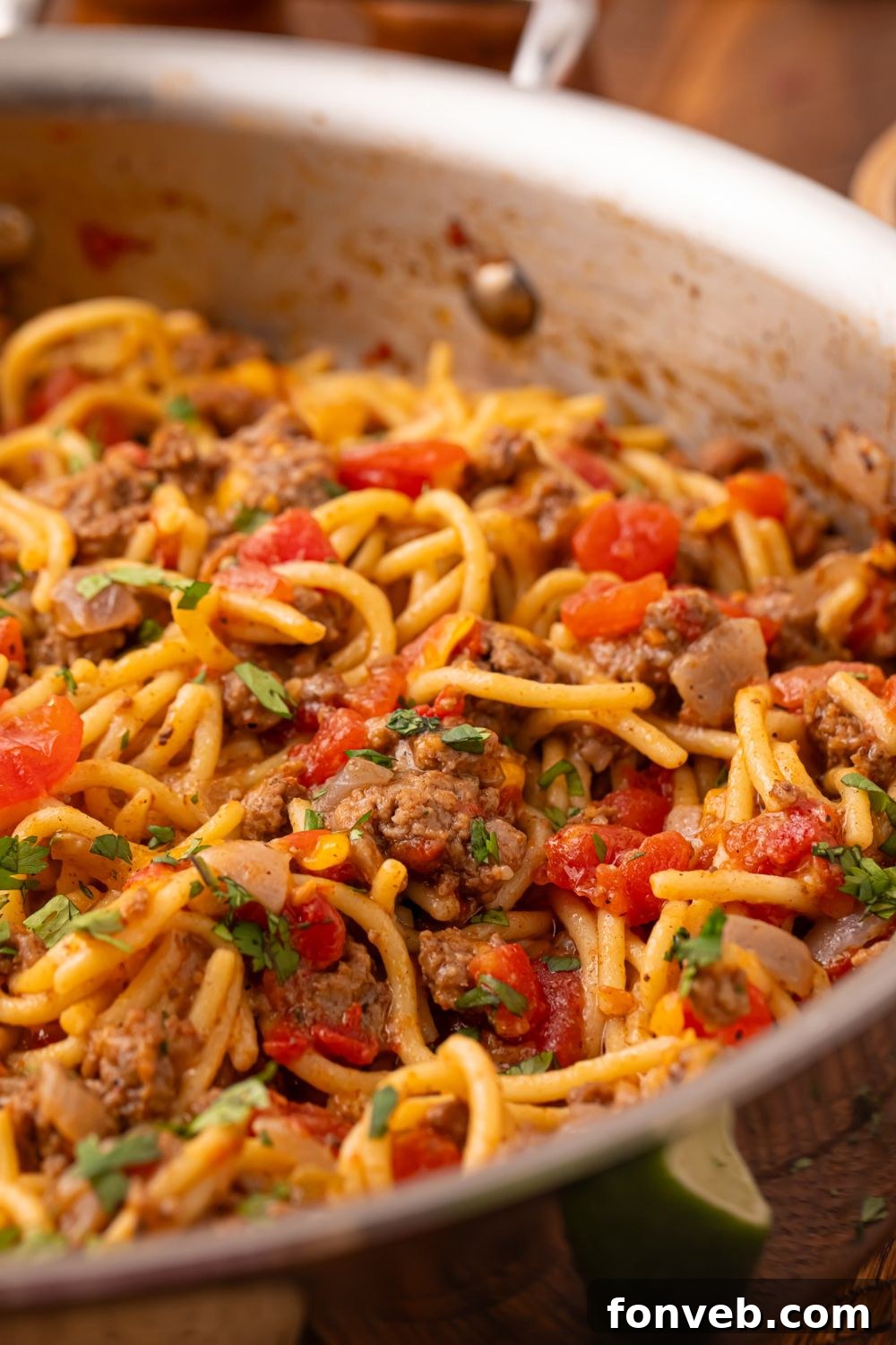 One Pot Cheesy Taco Spaghetti 9 a metal skillet with Cheesy Taco Spaghetti topped with fresh parsley on top