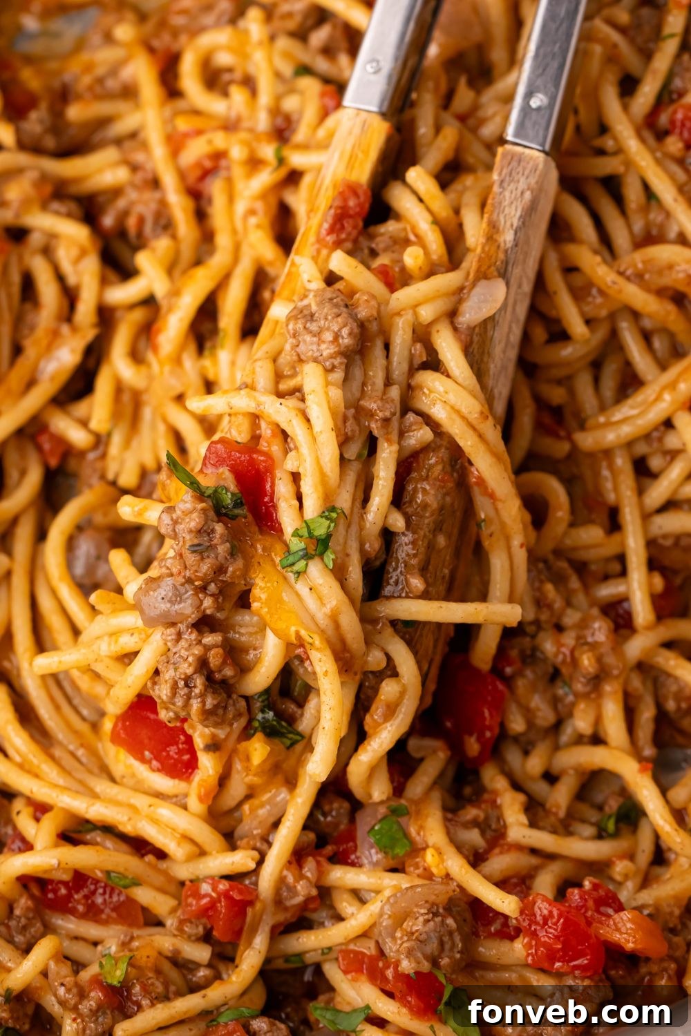 One Pot Cheesy Taco Spaghetti 10 Tex-Mex taco pasta in a pan with tongs full of some of the pasta mixture