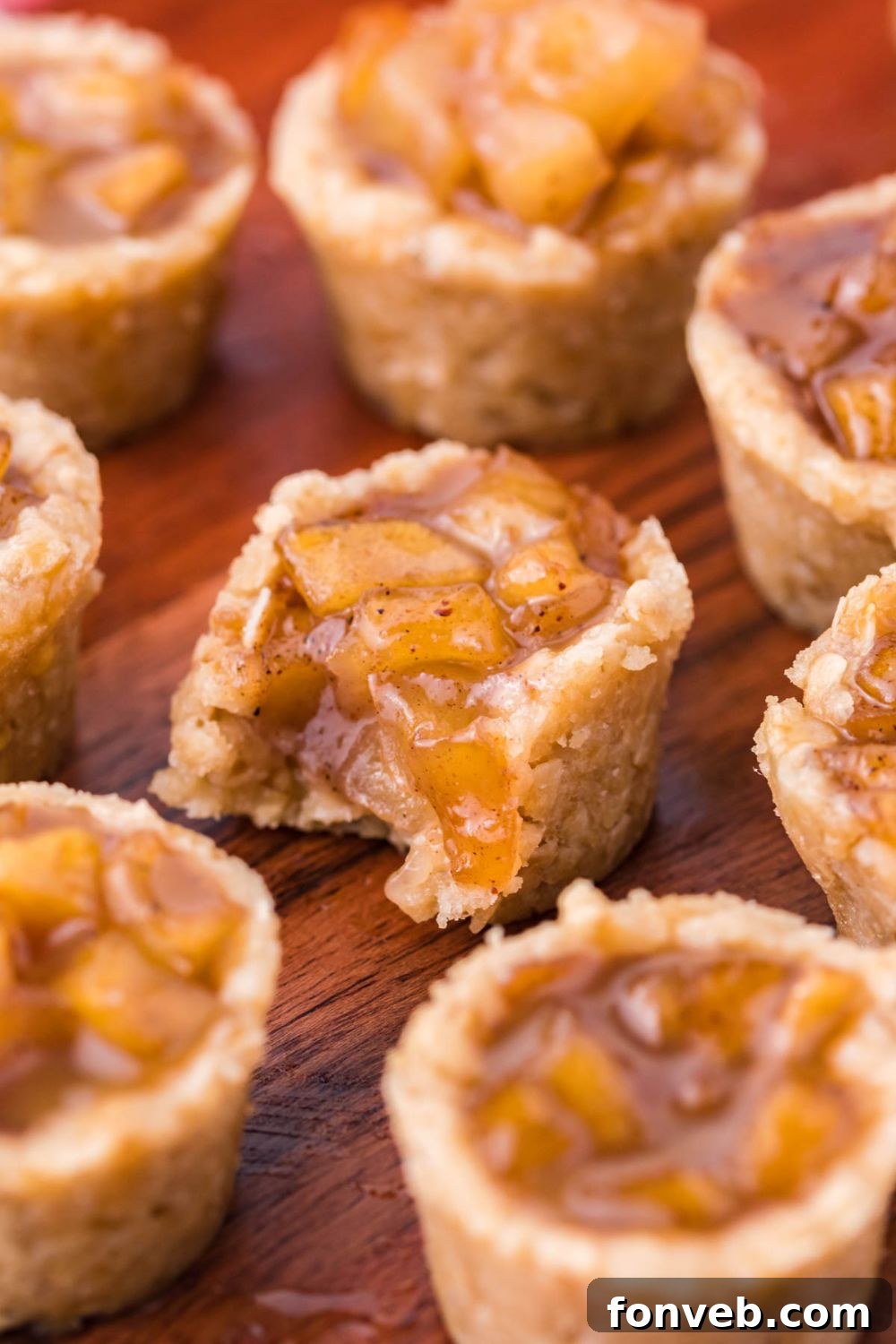 Mini Apple Crisp Bites placed around the table and one in center with a bite taken out of it 