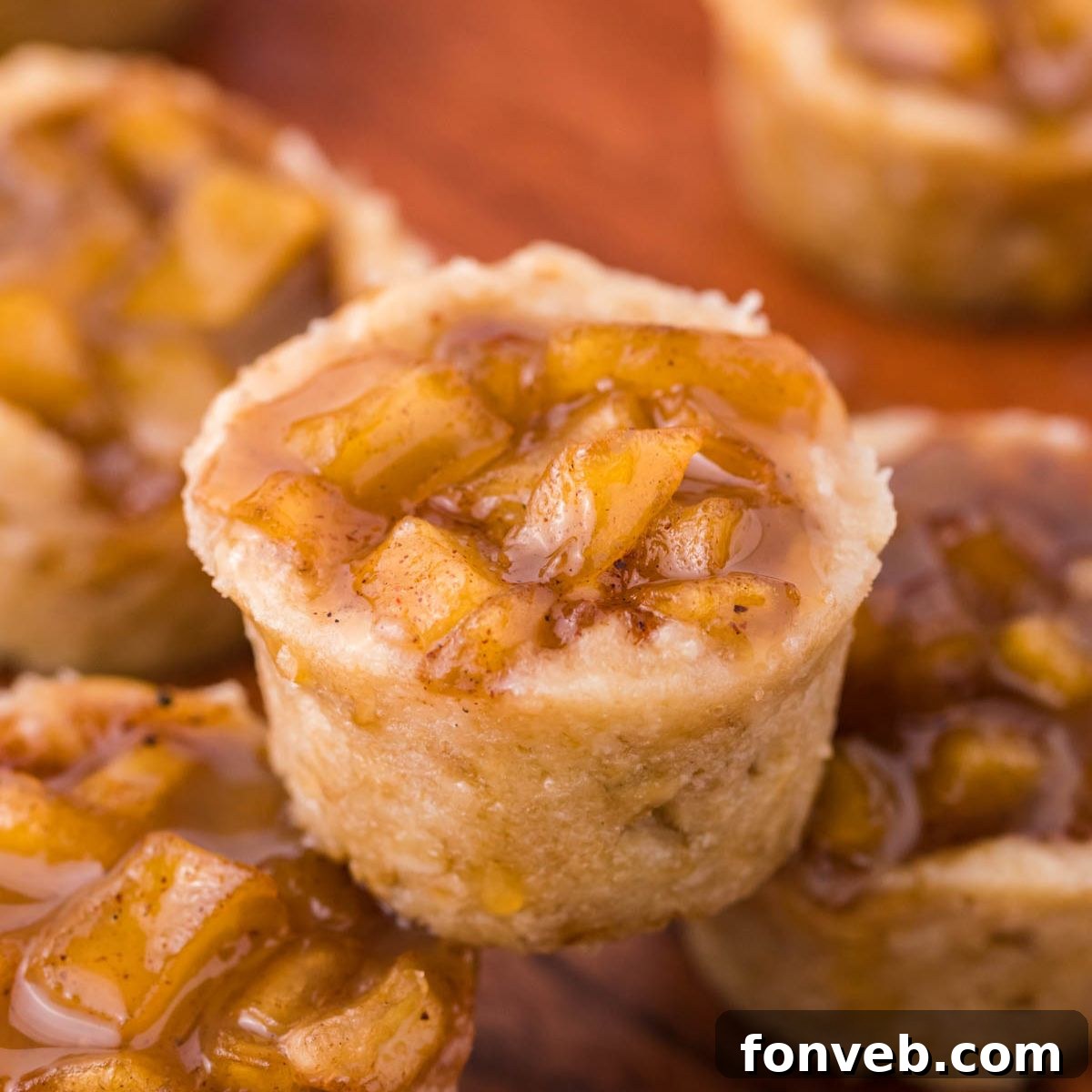 Mini Apple Crisp Bites placed around a wooden table with one stacked on top of another one 