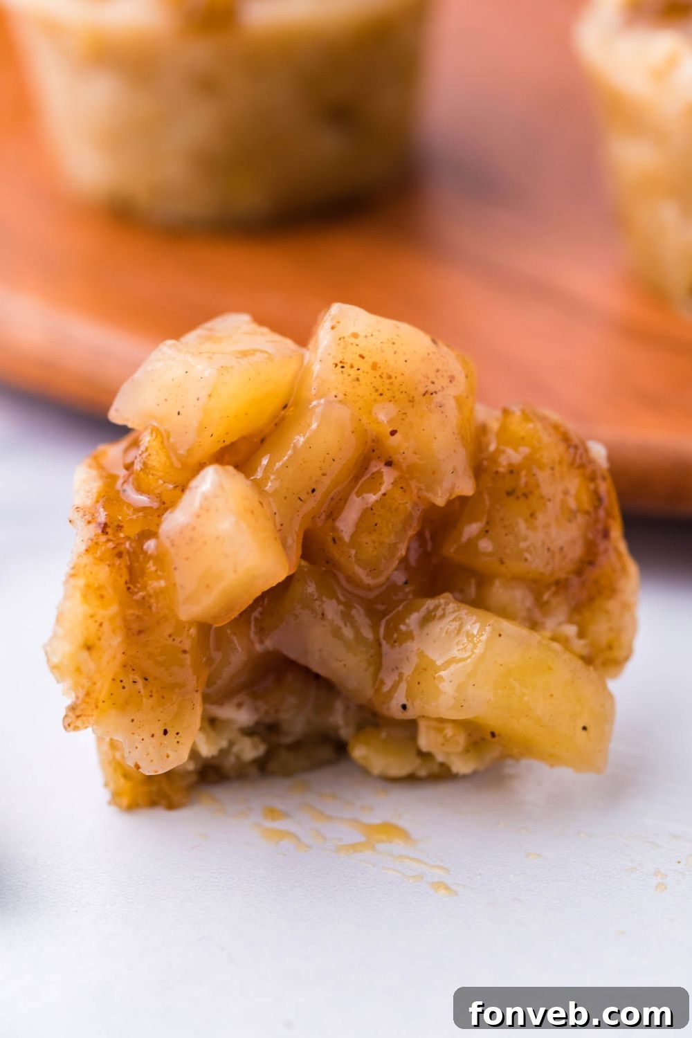 bite taken out of a mini apple crisp bite cup, with a bunch of the apple filling on top 