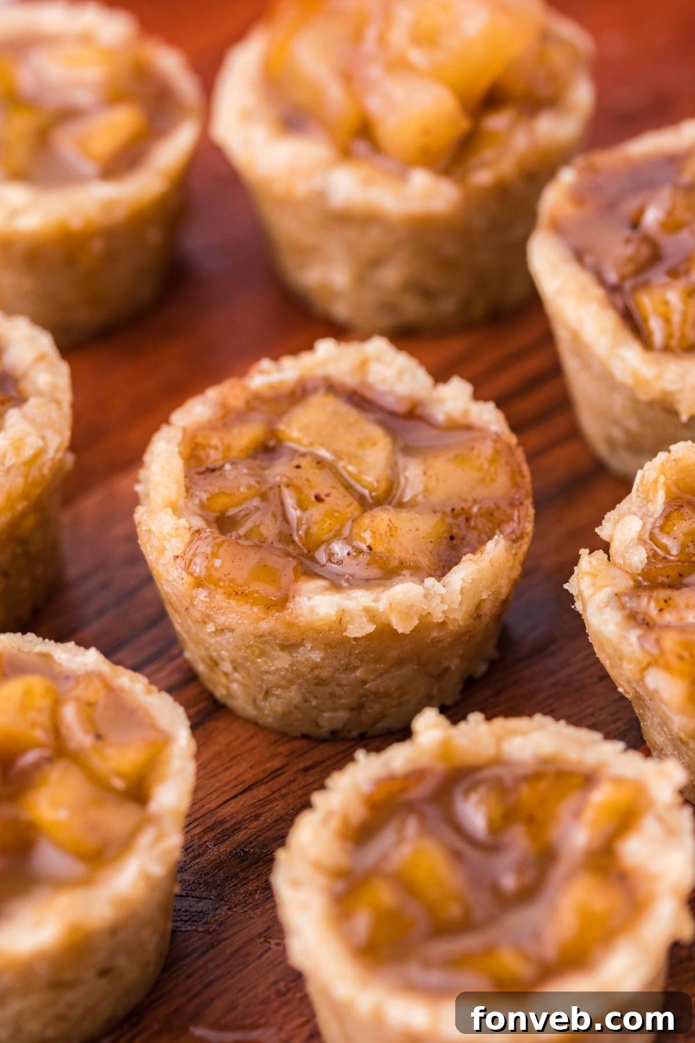 Mini Apple Crisp Bites scattered on a wooden platter on table showing the sweet apple filling and oat base 