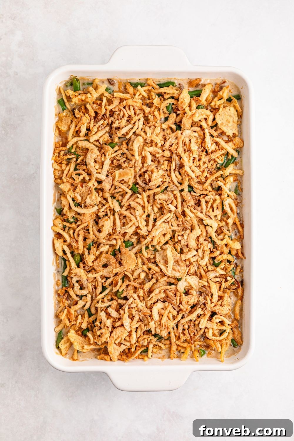 uncooked Green Bean Casserole in a white casserole dish on table 