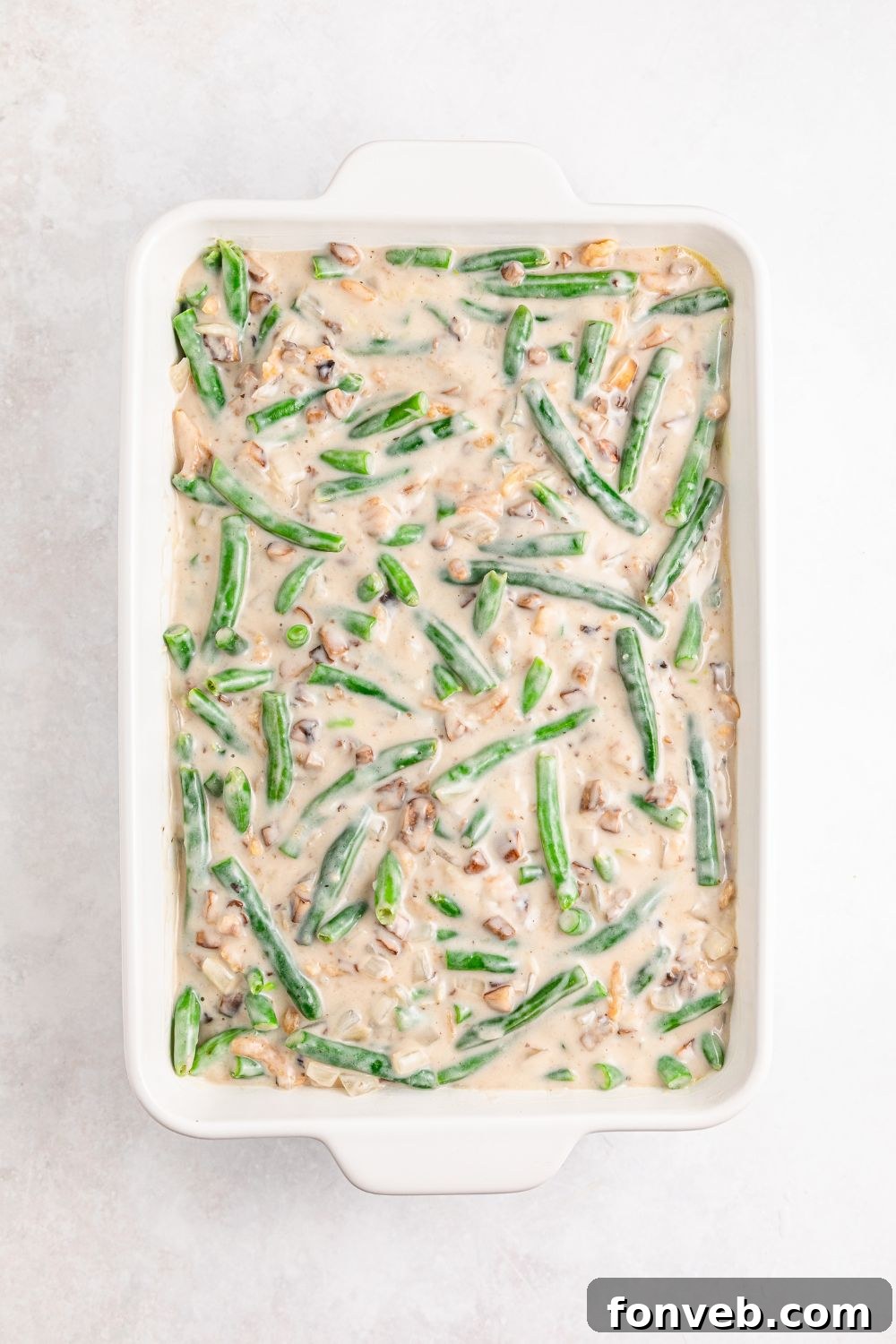 the mixture for Green Bean Casserole in a casserole dish with the green beans and the sauce 