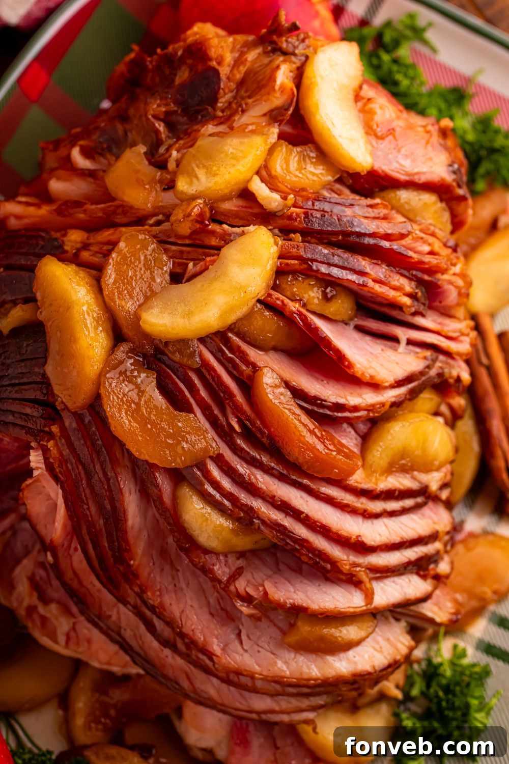 Tender and Juicy Slow Cooker Apple Glazed Ham 12 fully cooked Slow Cooker Apple Glazed Ham on a platter garnished with greens and cinnamon apples on top of ham