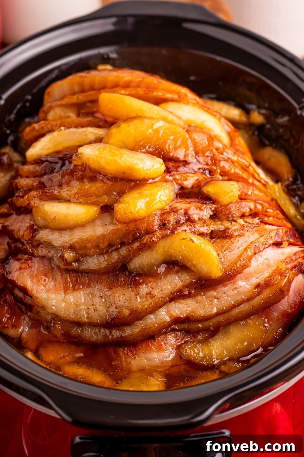 Tender and Juicy Slow Cooker Apple Glazed Ham 13 red slow cooker on table with a glazed apple spiral ham on table