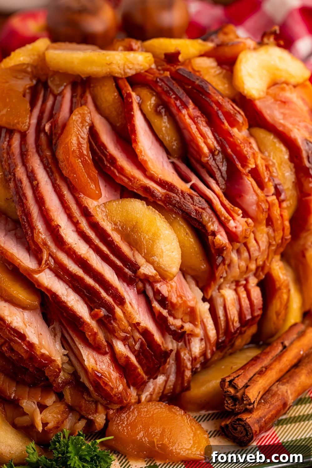 Tender and Juicy Slow Cooker Apple Glazed Ham 15 side view of a Slow Cooker Apple Glazed Ham sitting on a platter with cinnamon sticks in front