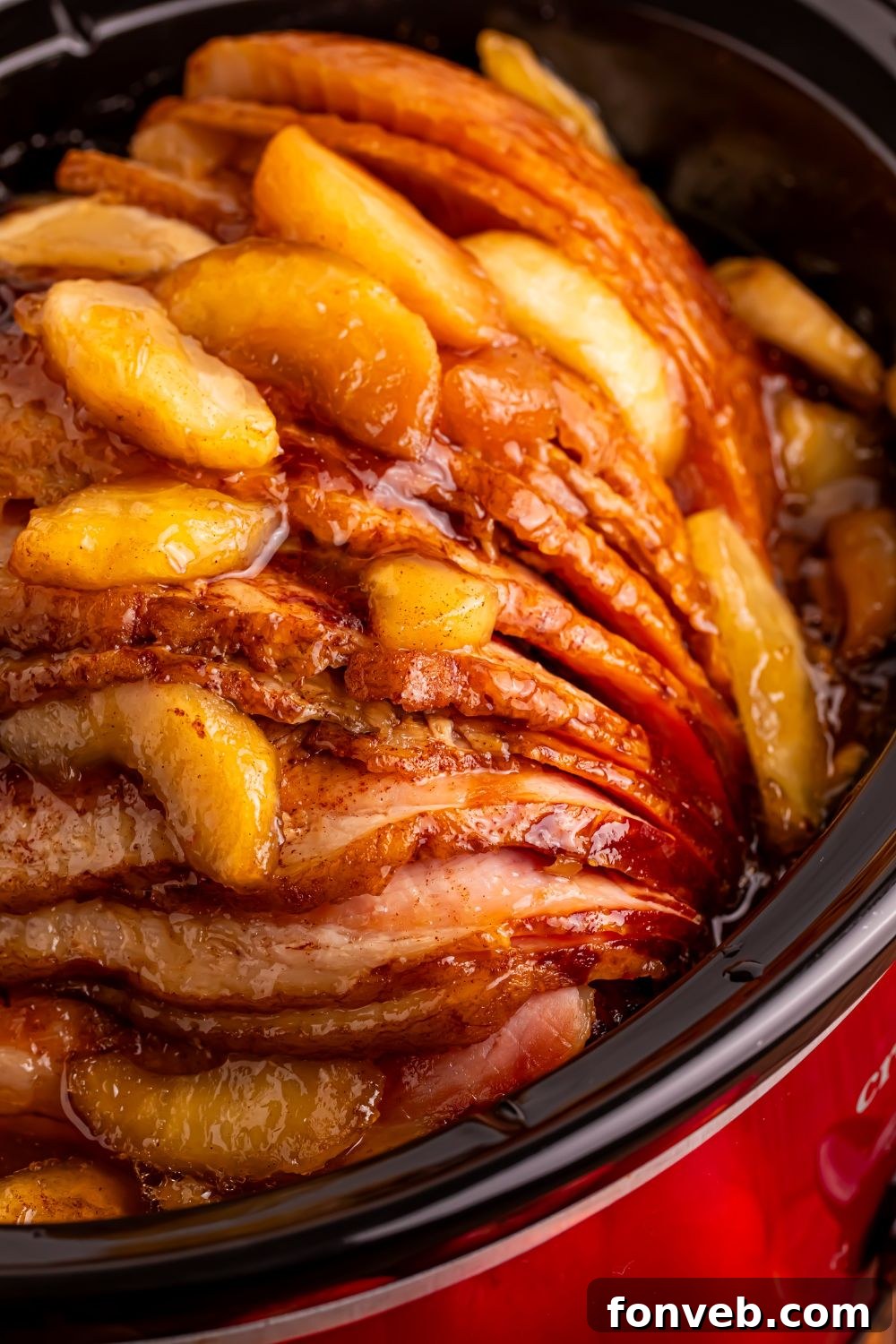 Tender and Juicy Slow Cooker Apple Glazed Ham 17 close up look of a red slow cooker with a apple topped spiral ham