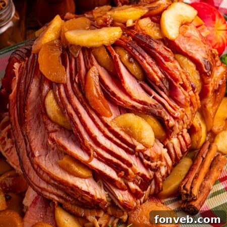 Tender and Juicy Slow Cooker Apple Glazed Ham 24 Slow Cooker Apple Glazed Ham on a plaid platter sitting on table with a checkered red towel behind ham, salt and pepper shakers