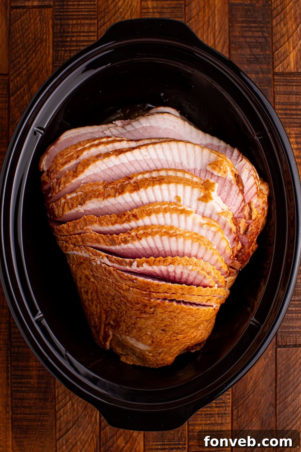 Tender and Juicy Slow Cooker Apple Glazed Ham 6 raw spiral cut ham sitting on a wooden table in a black slow cooker