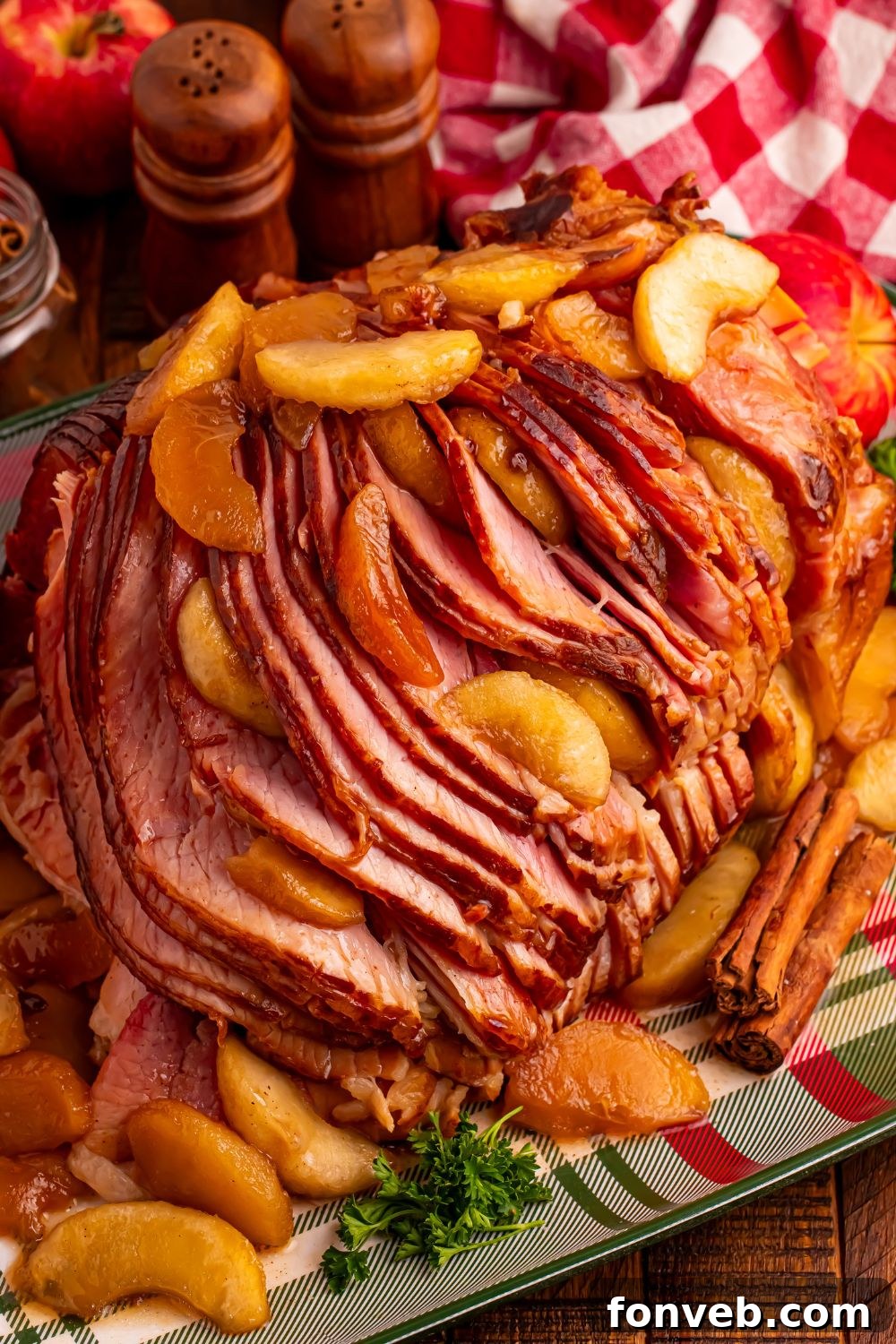Tender and Juicy Slow Cooker Apple Glazed Ham 10 Slow Cooker Apple Glazed Ham on a plaid platter sitting on table with a checkered red towel behind ham, salt and pepper shakers