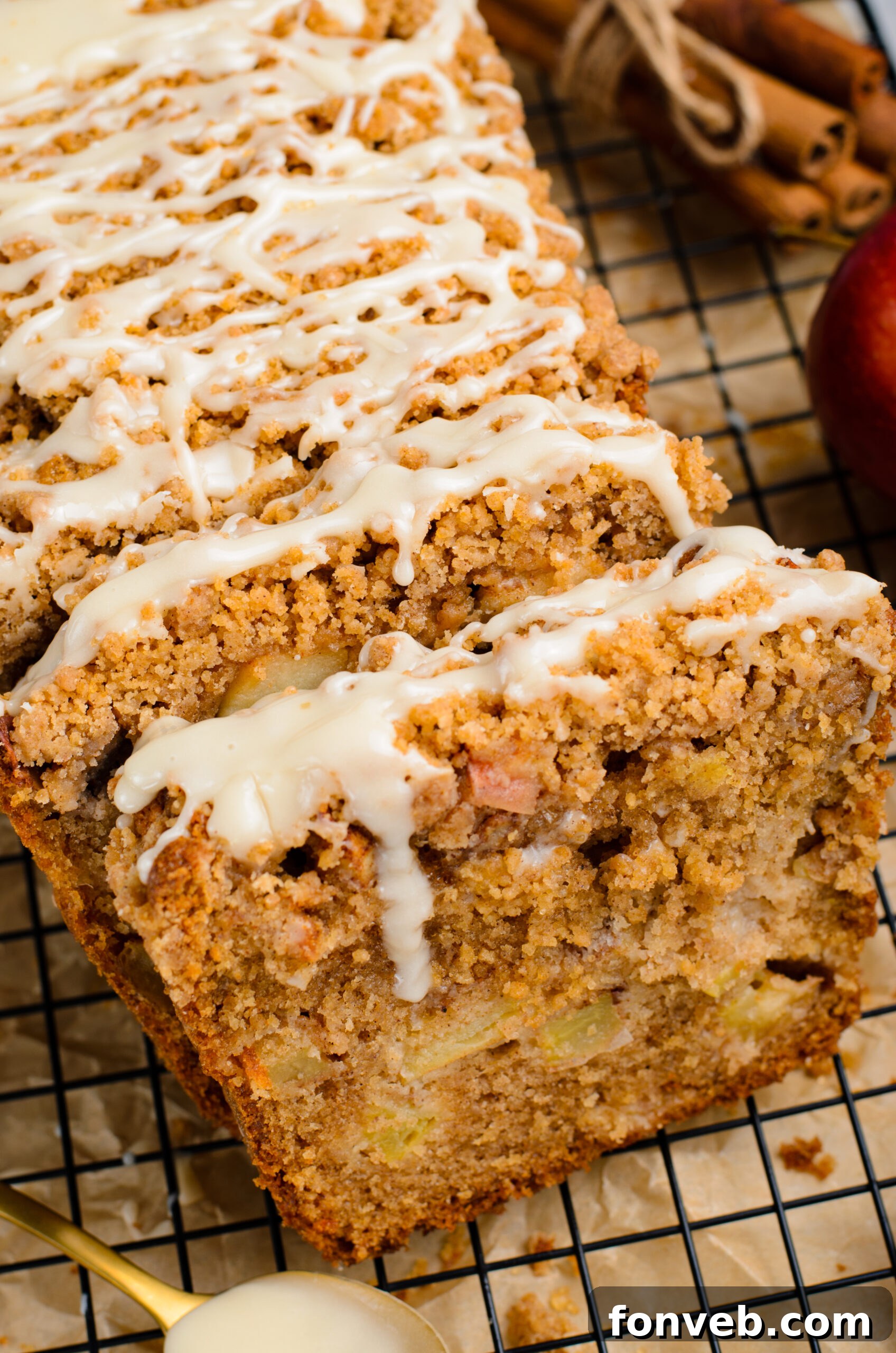 Quick Glazed Apple Cinnamon Loaf 30 A close-up view of the entire, beautifully baked Apple Cinnamon Loaf Cake, perfectly glazed and resting on a black cooling rack, showcasing its golden-brown crumb topping.