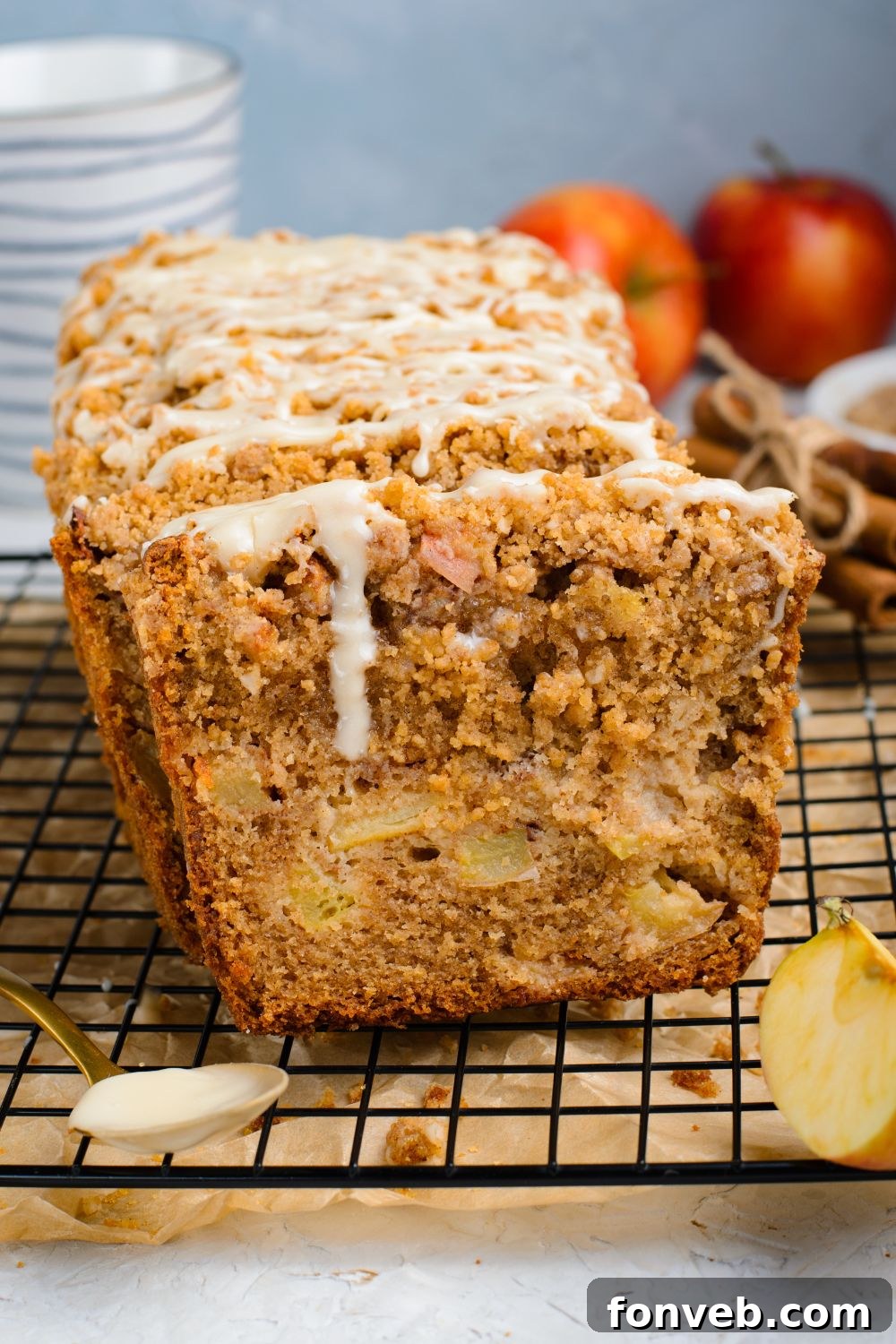 Quick Glazed Apple Cinnamon Loaf 5 A beautifully glazed Apple Cinnamon Loaf Cake, freshly sliced, rests on a metal cooling rack with parchment paper underneath, ready to be served.