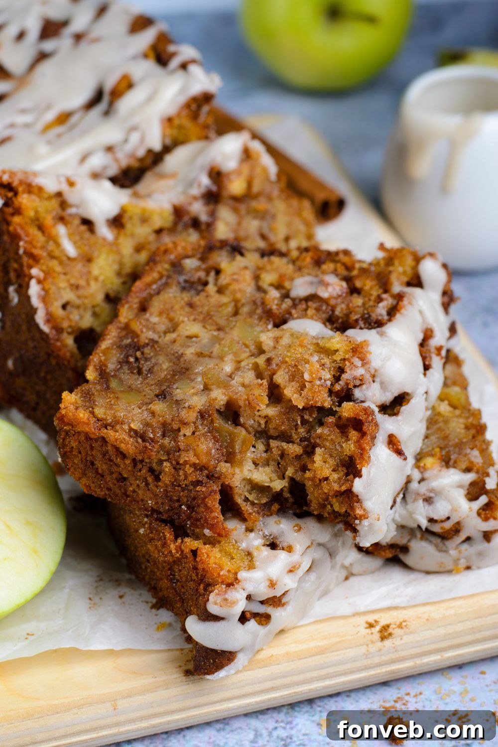 Apple bread with real apples sliced and placed on table with a bite taken out of the top slice of bread and apples around it on table for decor 
