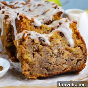 Amish Apple Fritter Bread sliced and placed on a parchment paper on table with a bowl with glaze to the side