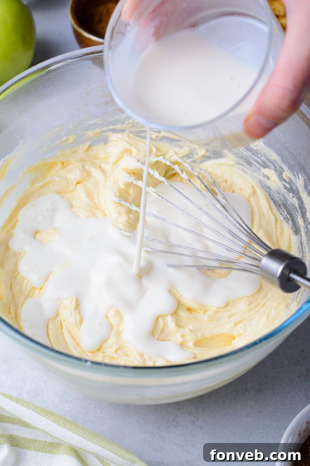 milk mixture pouring into an apple bread batter on table 