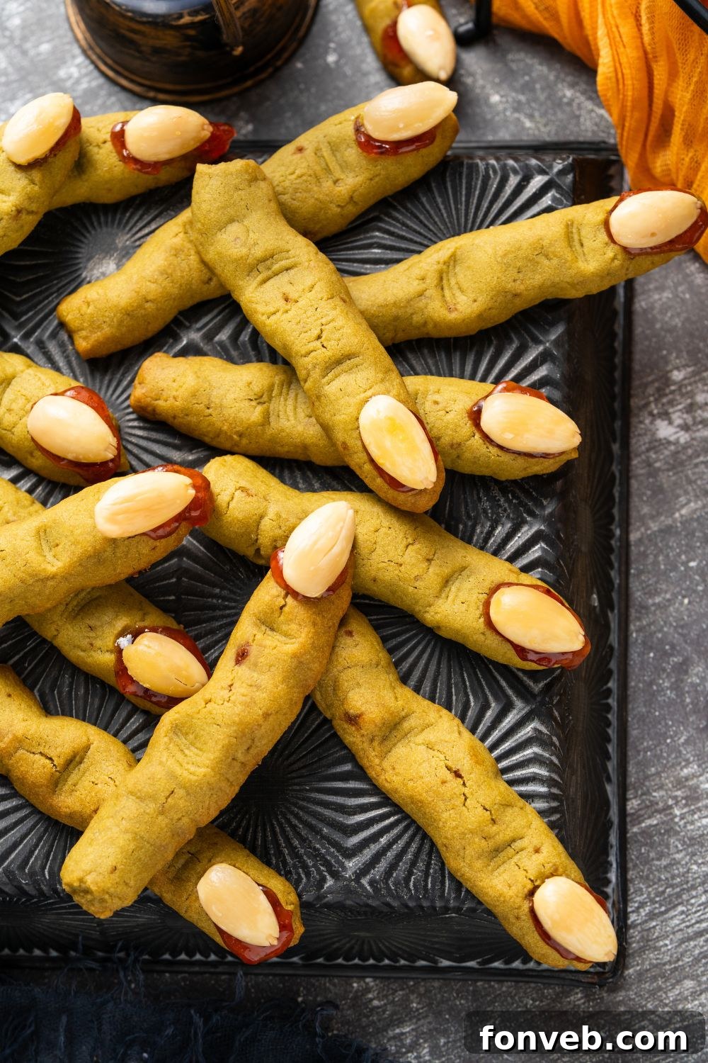 Witch Finger Cookies A Ghoulishly Fun Halloween Bake 17 black tray with Witch Finger Cookies scattered on it with some Halloween decor on the table around the tray