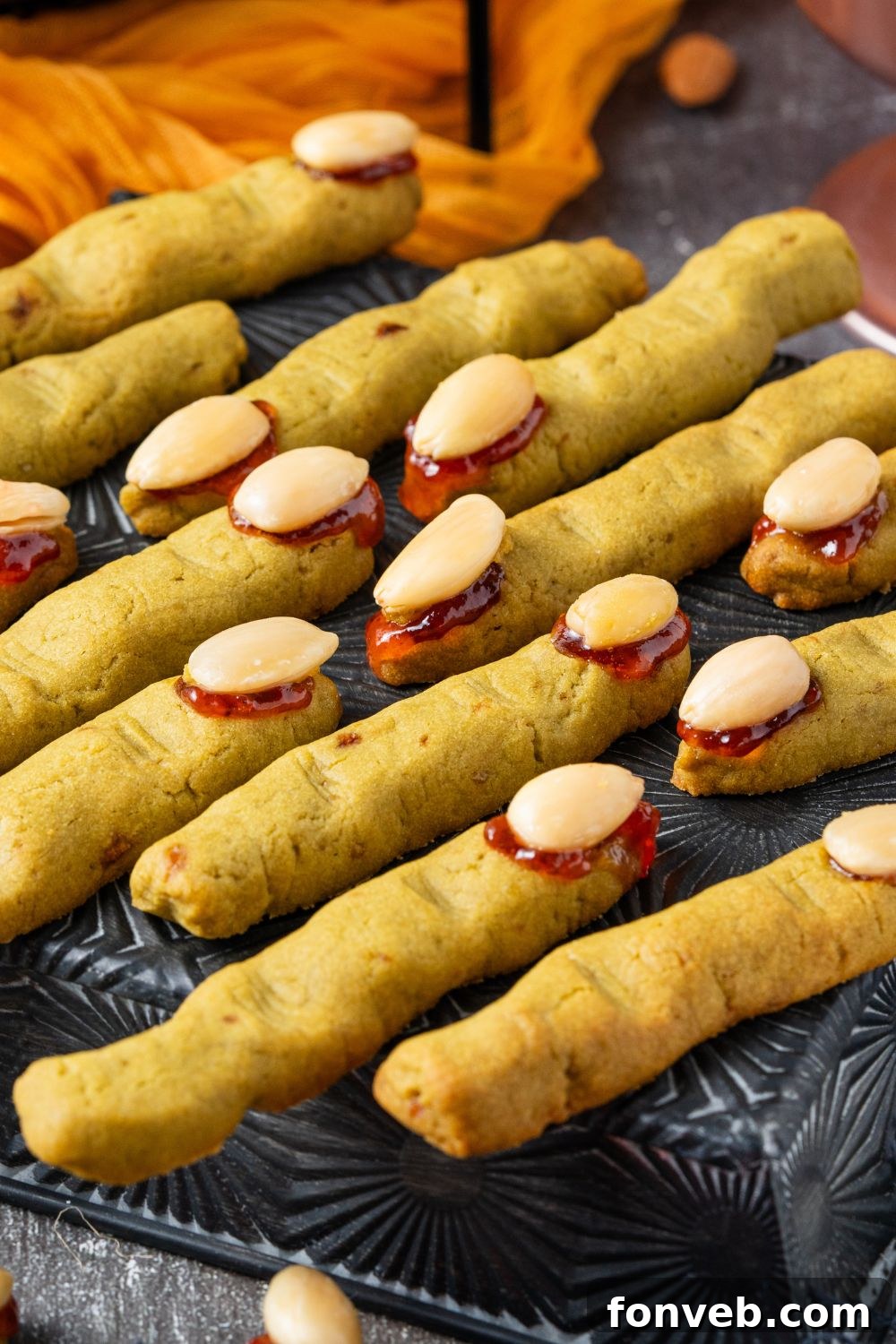 Witch Finger Cookies A Ghoulishly Fun Halloween Bake 18 Witch Finger Cookies on a black tray on table with an orange towel behind it on the grey table