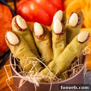 Witch Finger Cookies in a basket with straw in it with pumpkins and leaves on the table behind it