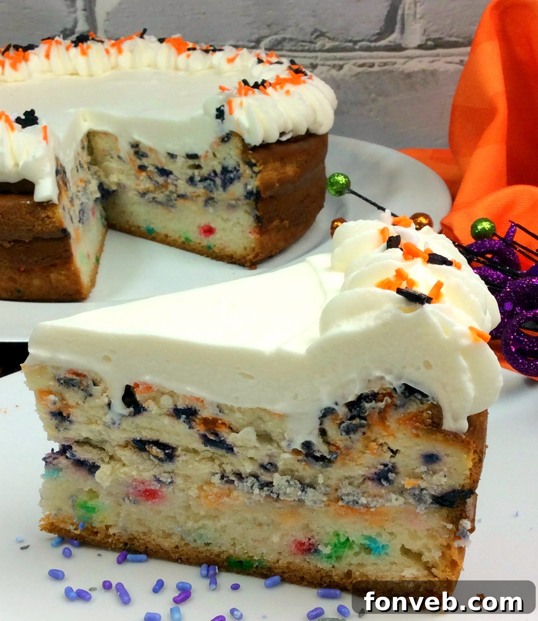 A whole Halloween Funfetti Cheesecake with decorative whipped cream swirls and sprinkles