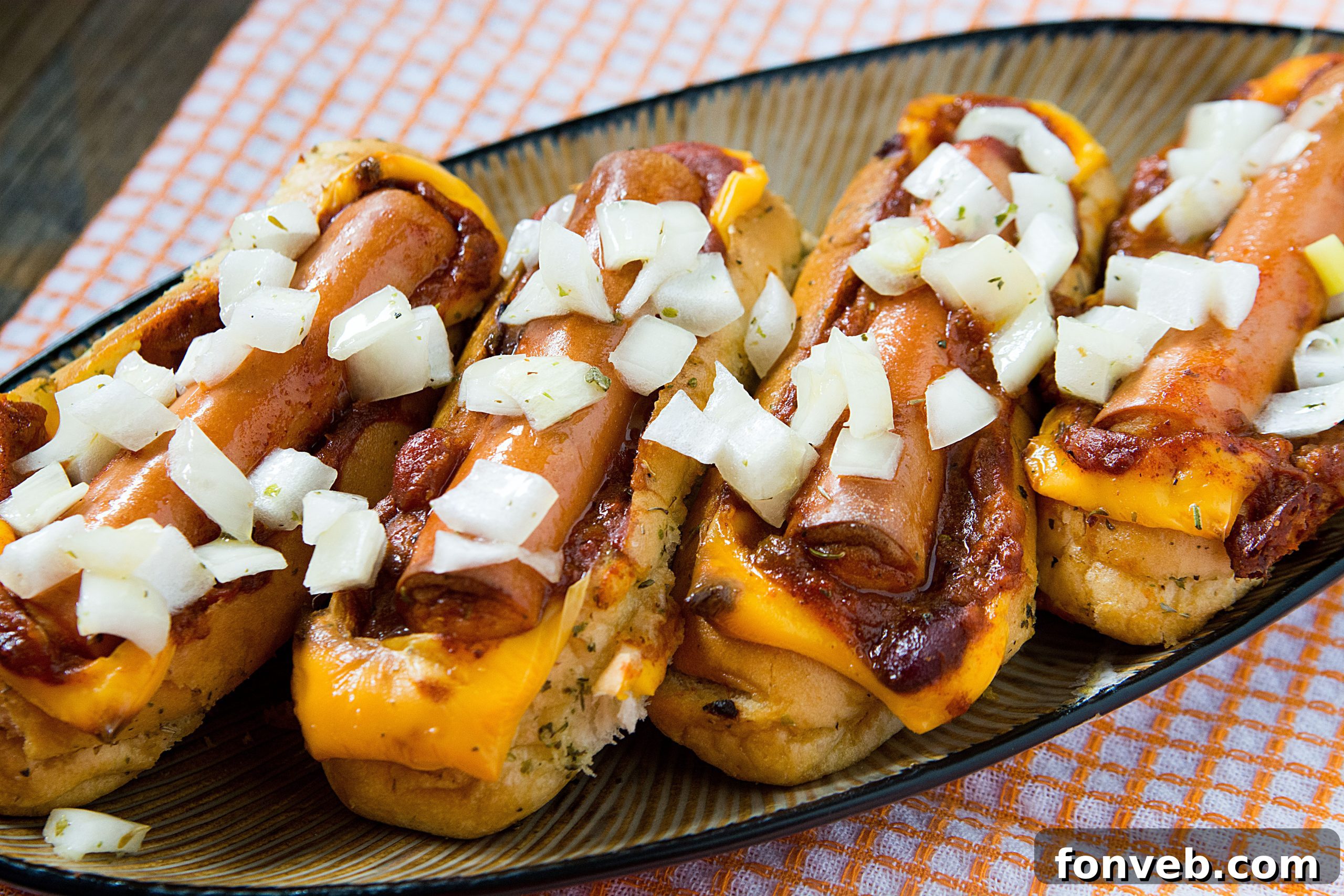 Two fully loaded chili cheese dog boats, showing the rich chili, melted cheese, and fresh hot dogs nestled in toasted buns.