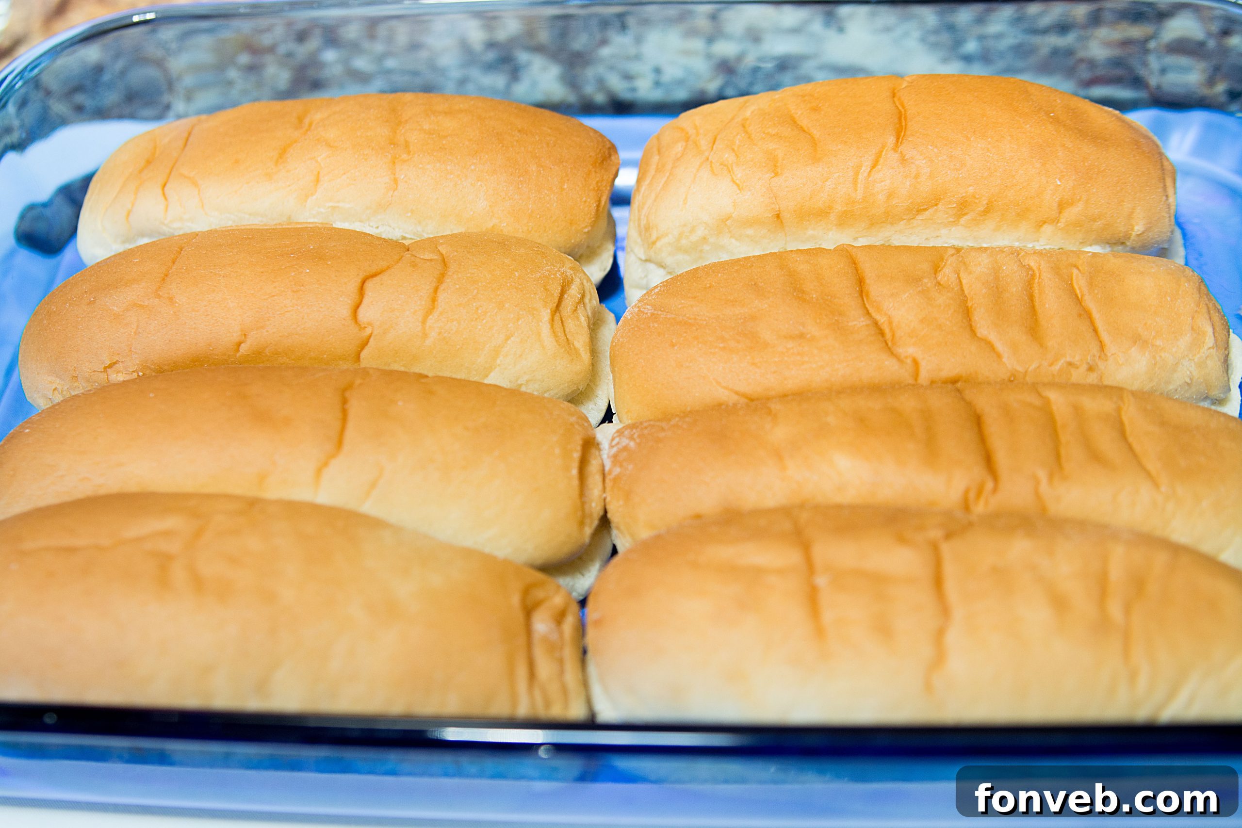 Overhead shot of all the ingredients laid out: hot dog buns, block of cheddar cheese, can of chili, fresh parsley, garlic, onion, and butter.