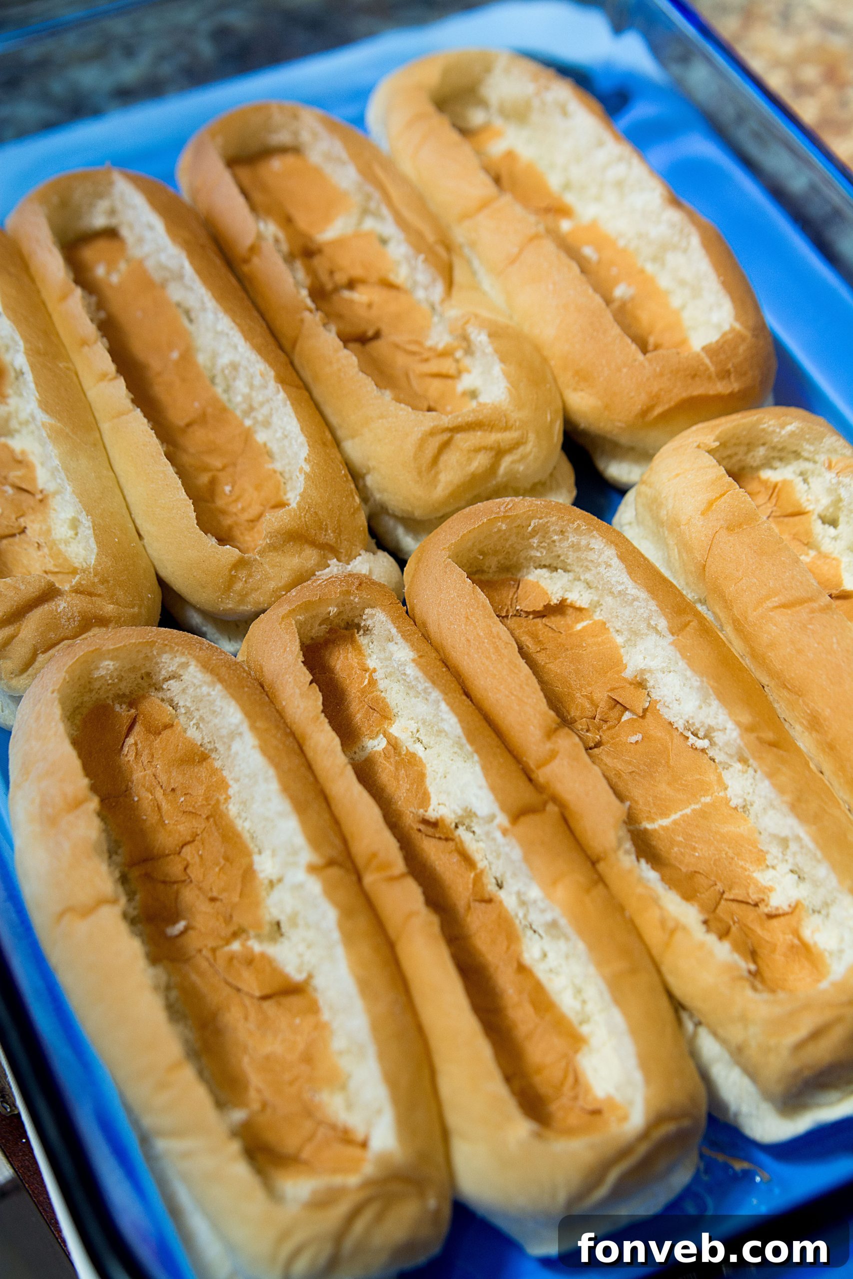 Hot dog buns arranged neatly in a 9x13 baking dish, ready for preparation.