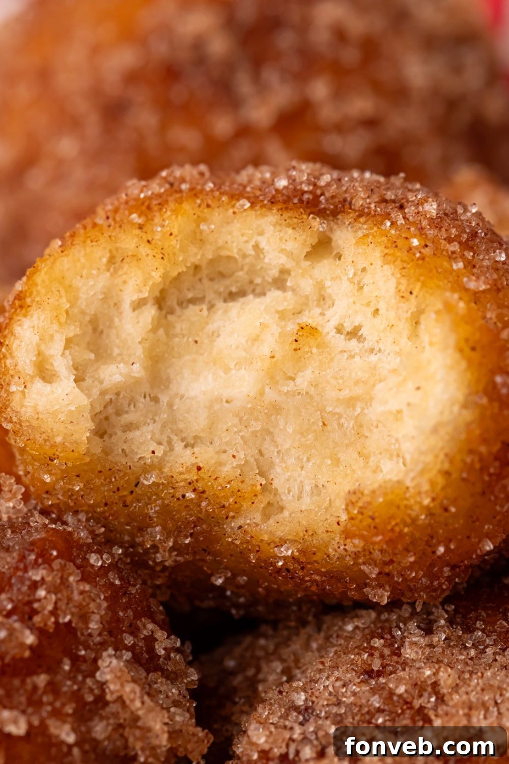 a bite taken out of an Apple Pie Donut Hole that is showing a close up view to show how fluffy it is 