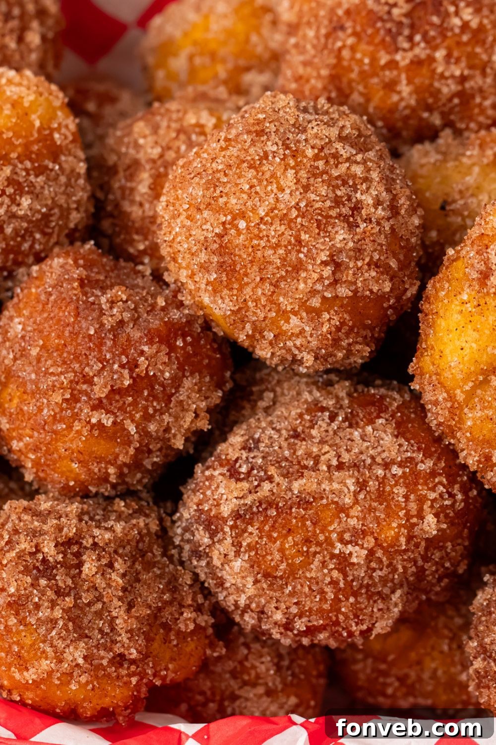 Apple Pie Donut Holes dusted with cinnamon and sugar stacked on top of one another 