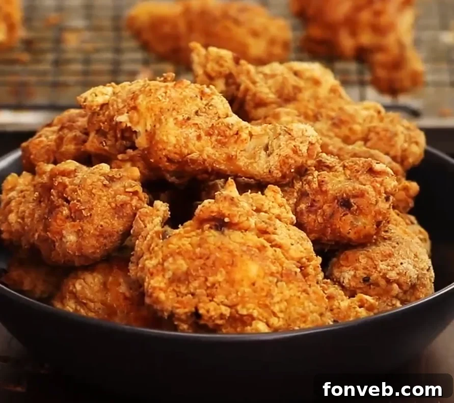 Perfectly golden brown Popeyes style fried chicken on a cooling rack