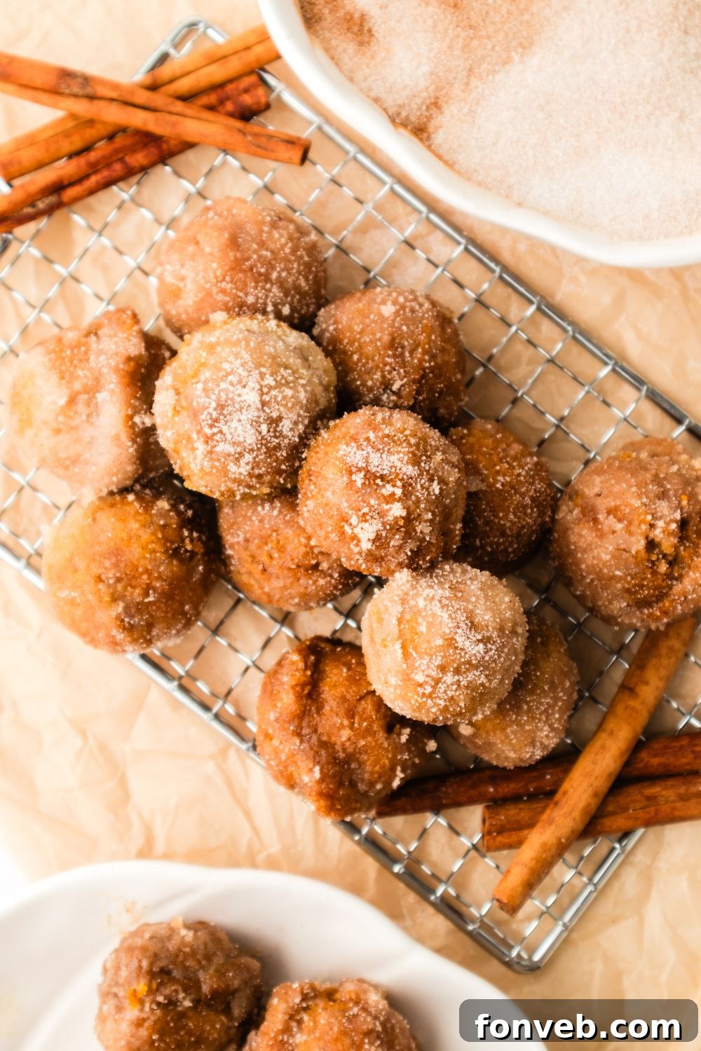 Cinnamon Sugar Baked Pumpkin Spice Donut Holes 20 Pumpkin Spice Donut Holes on a metal tray with a few cinnamon sticks to the side