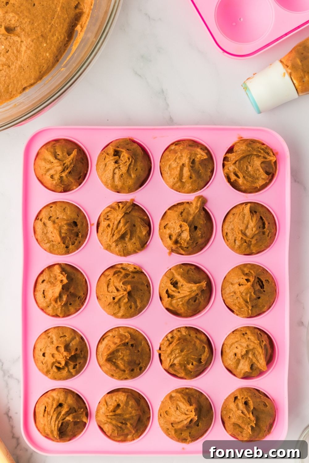 Cinnamon Sugar Baked Pumpkin Spice Donut Holes 8 raw batter for Pumpkin Spice Donut Holes in a pink donut pan sitting on a marble counter